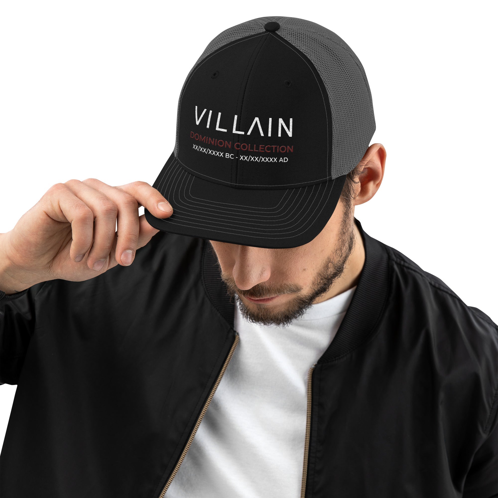 Man in black jacket and white shirt wearing a black and grey trucker cap with 'Villain Dominion Collection' text.