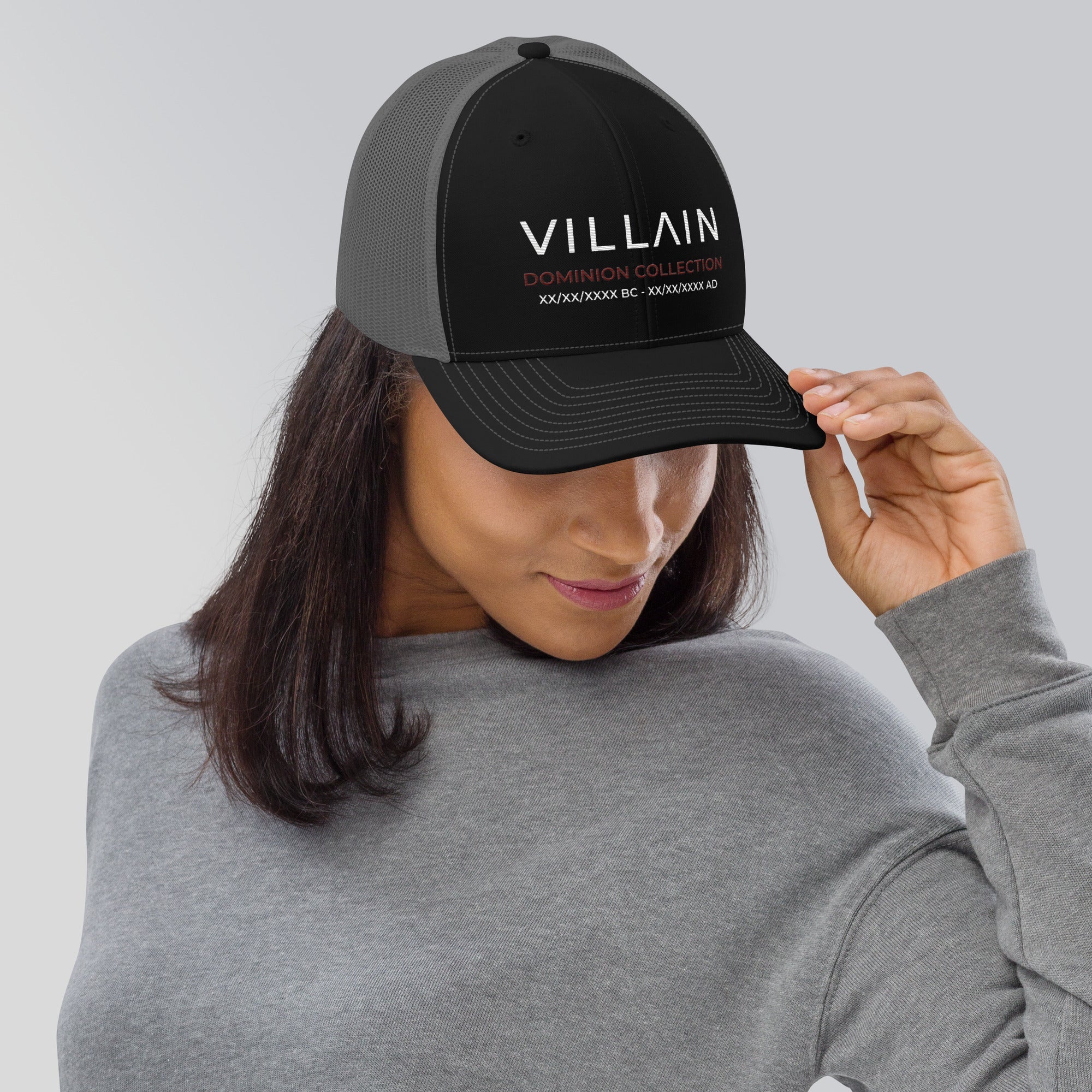 Woman wearing black trucker cap with VILLAIN DOMINION COLLECTION text, streetwear style