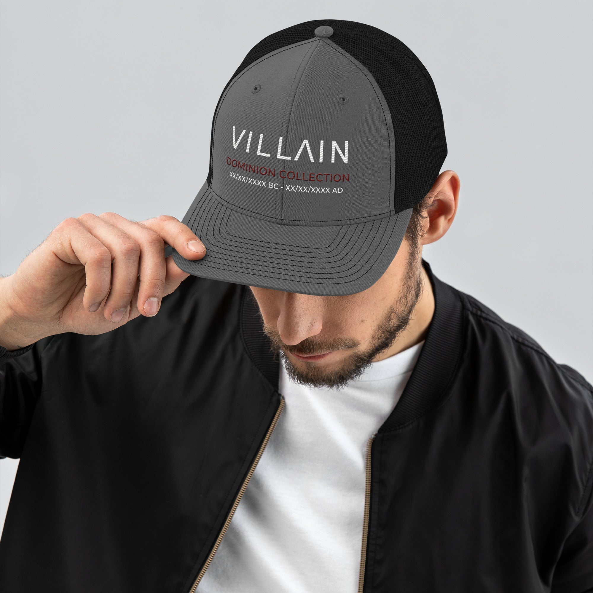 Man wearing a gray and black trucker cap with 'Villain Dominion Collection' text on front