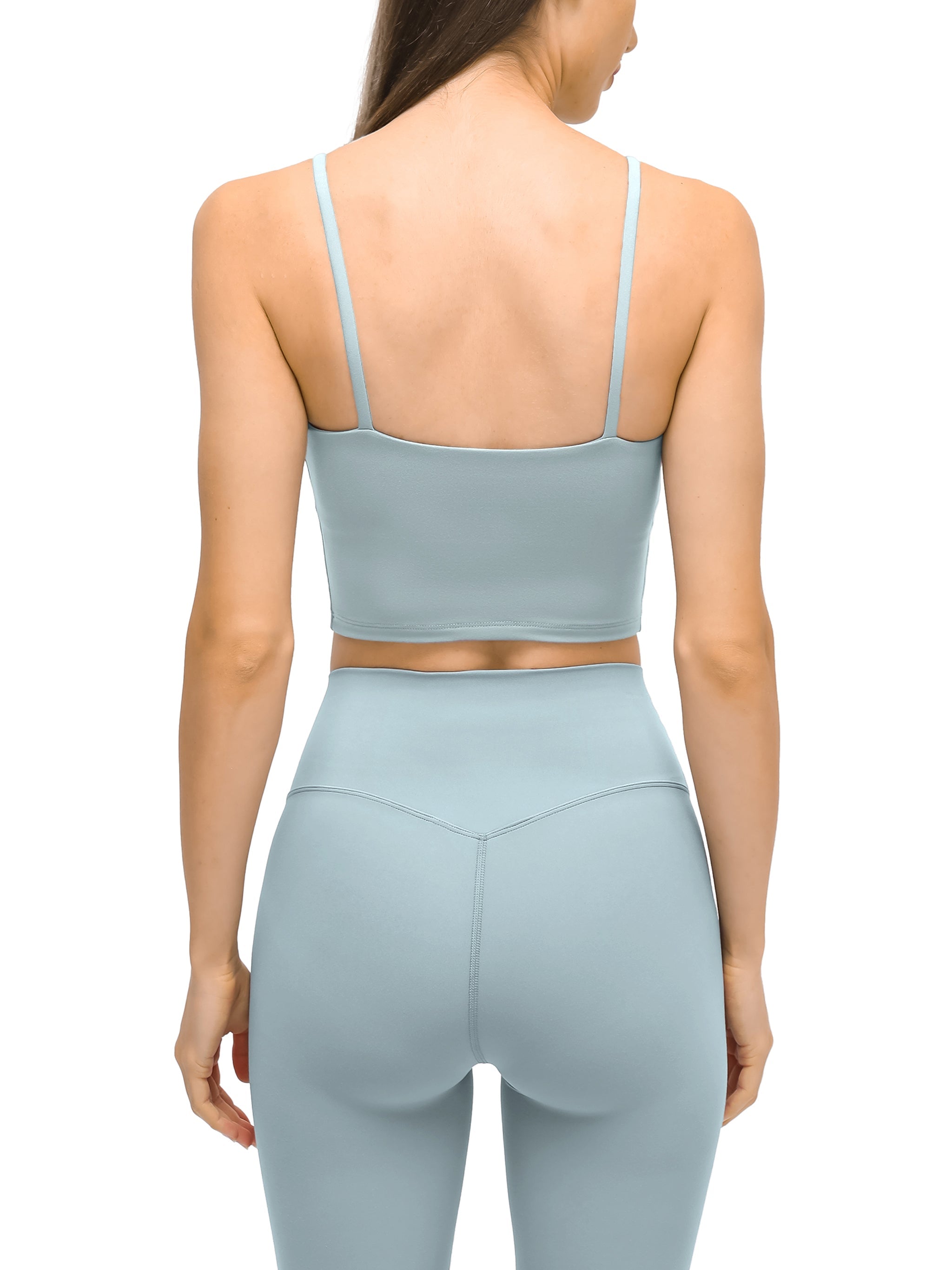 Back view of woman wearing light blue spaghetti strap yoga sports bra and high-waist leggings