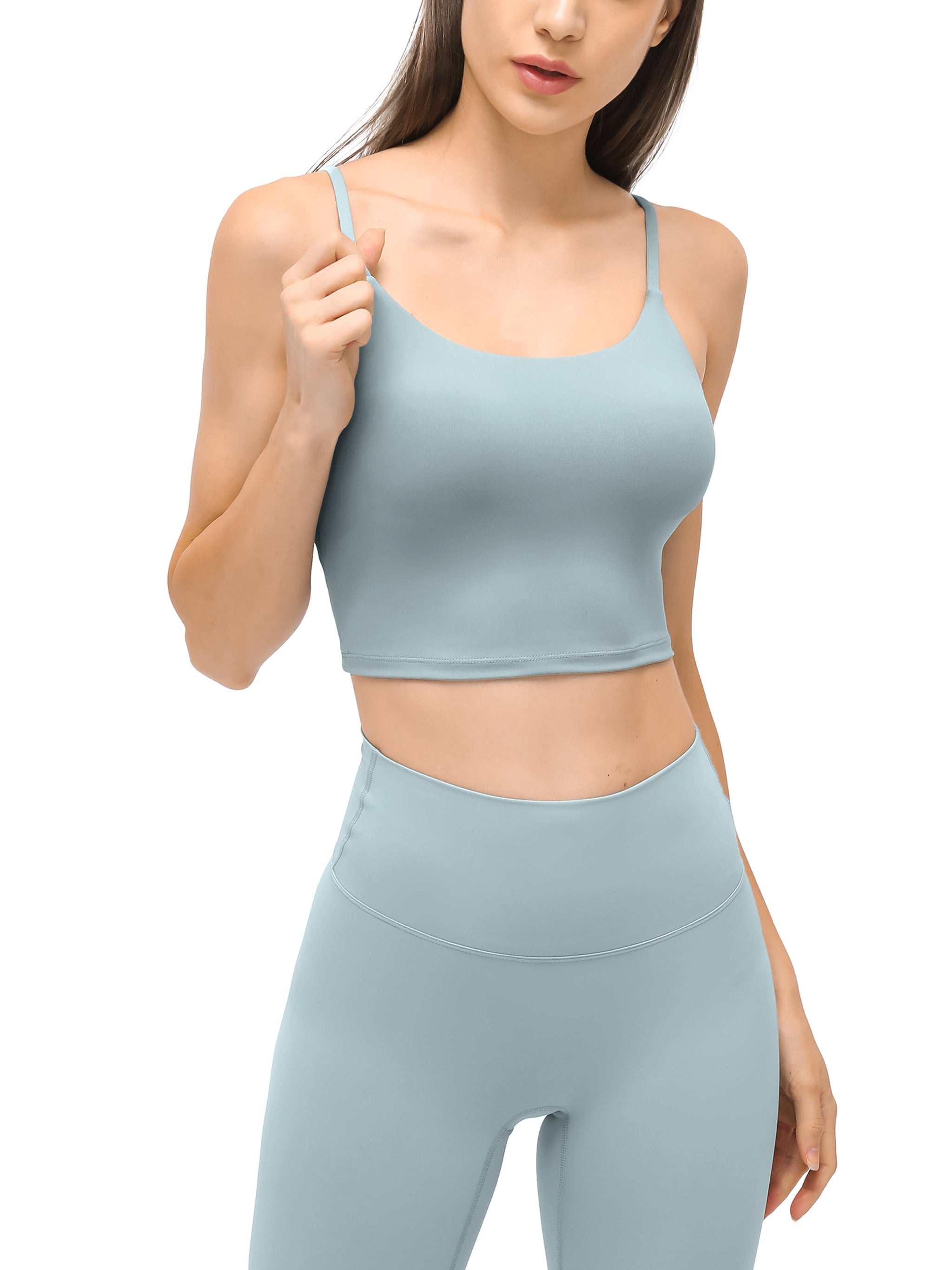 Woman wearing light blue spaghetti strap yoga sports bra and high-waisted leggings