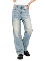 Wide-leg faded denim jeans with raw hems and subtle distressing, styled with black shoes.