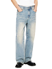 Light wash straight leg denim jeans with raw hem and faded detailing, worn by model
