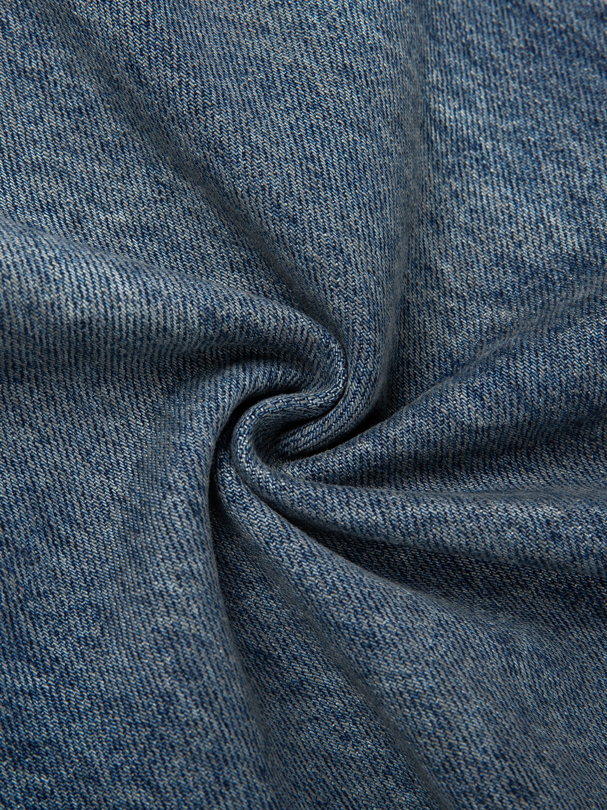 Close-up of vintage-wash blue denim fabric with textured weave and natural folds