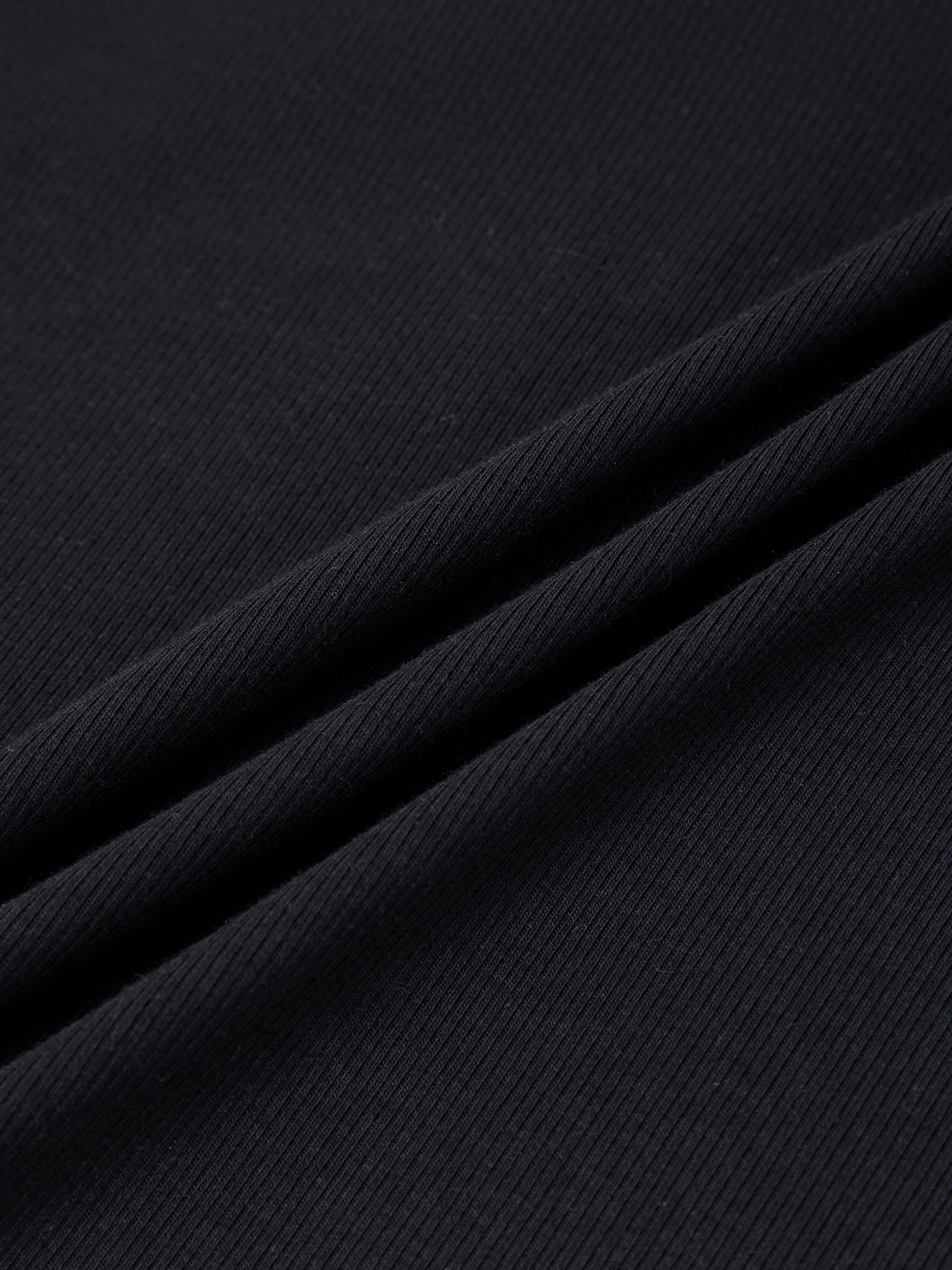 Close-up of black ribbed heavyweight t-shirt fabric texture with soft folds