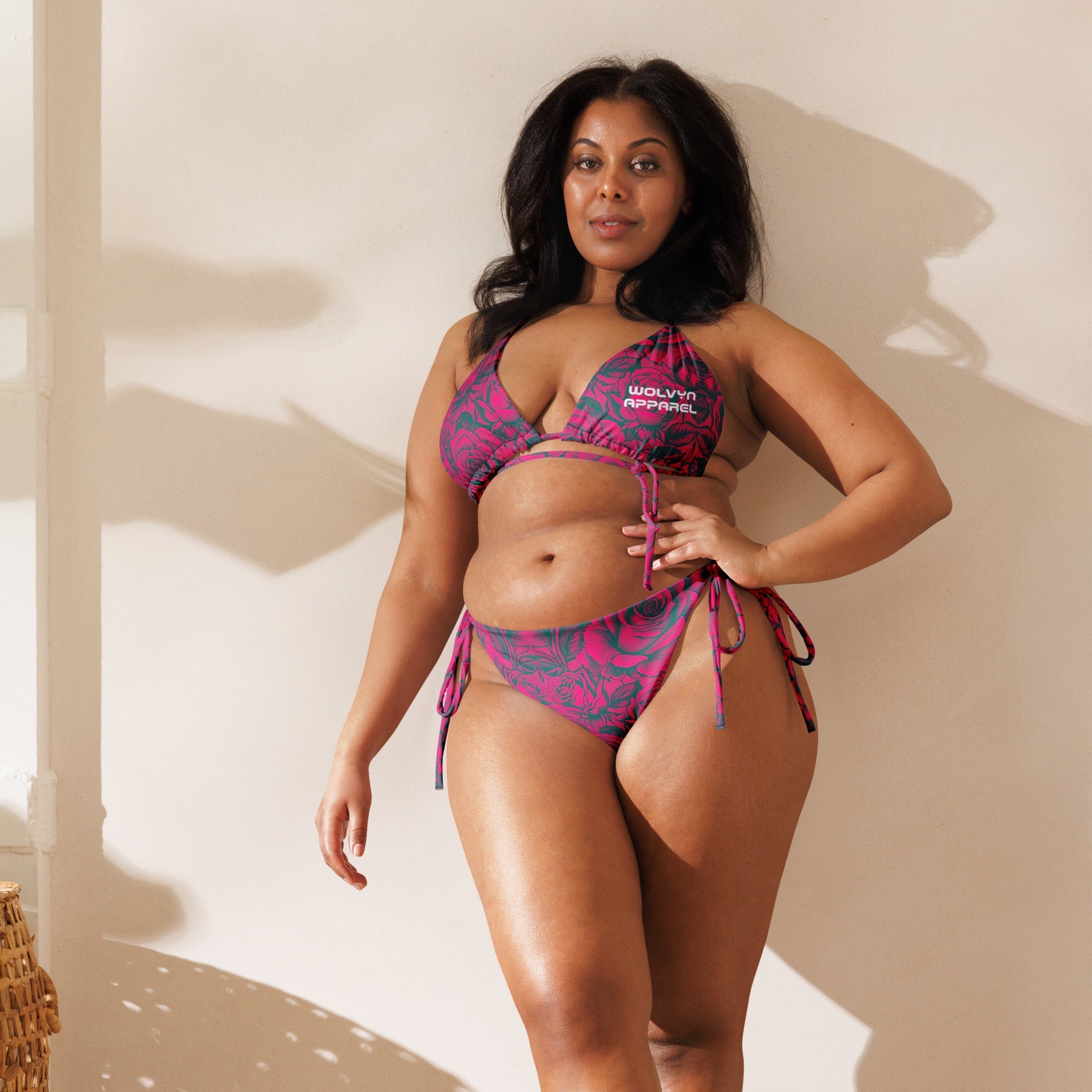 Woman wearing a pink floral string bikini with side ties, posing indoors in natural light.