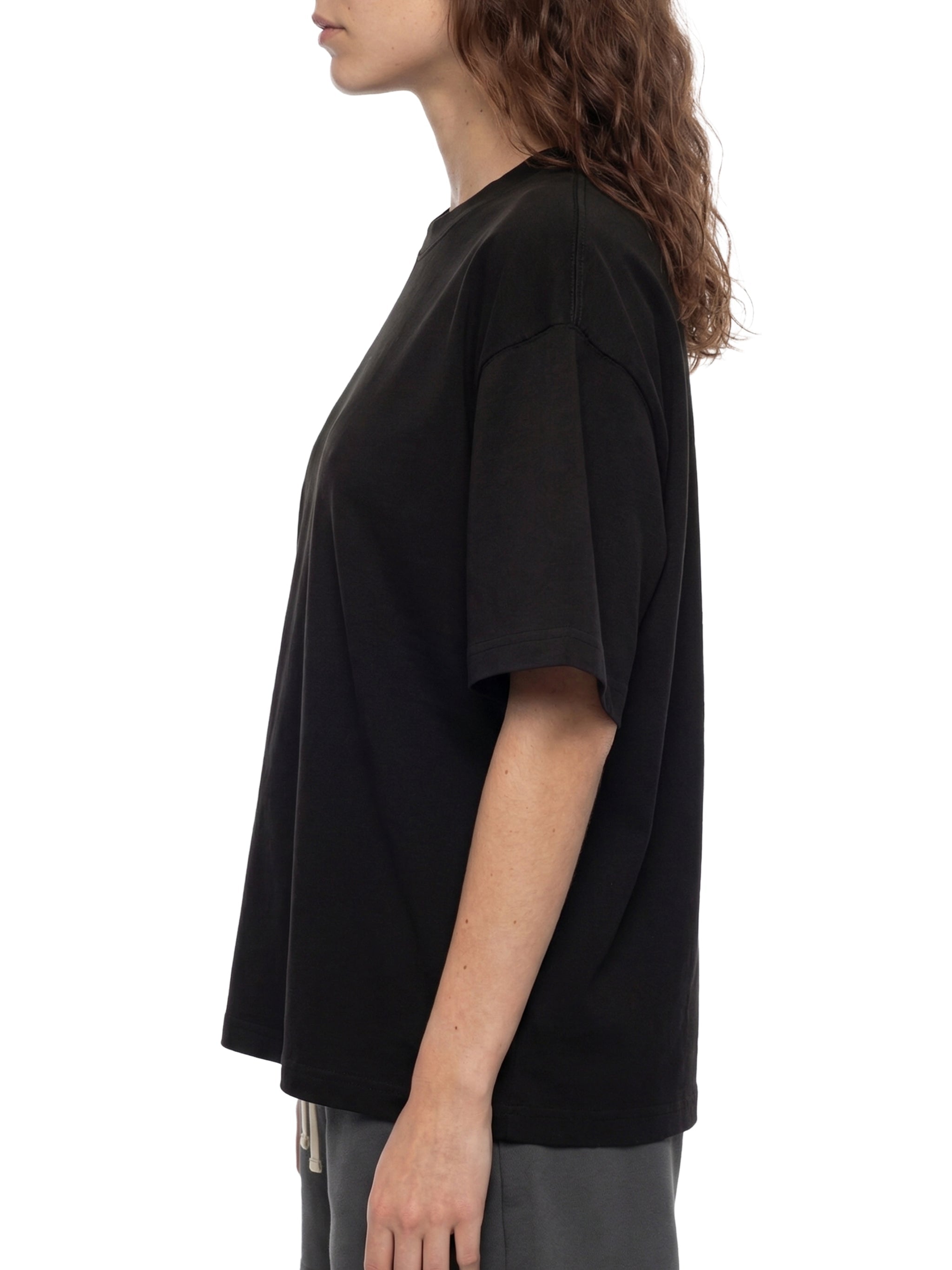 Side view of person wearing black oversized boxy unisex t-shirt and gray pants