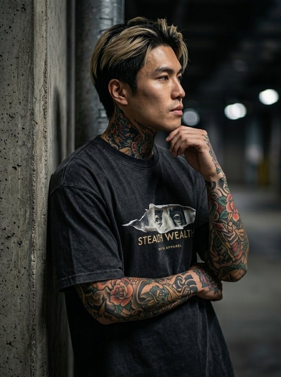 Tattooed man in faded black Stealth Wealth graphic t-shirt posing in urban setting