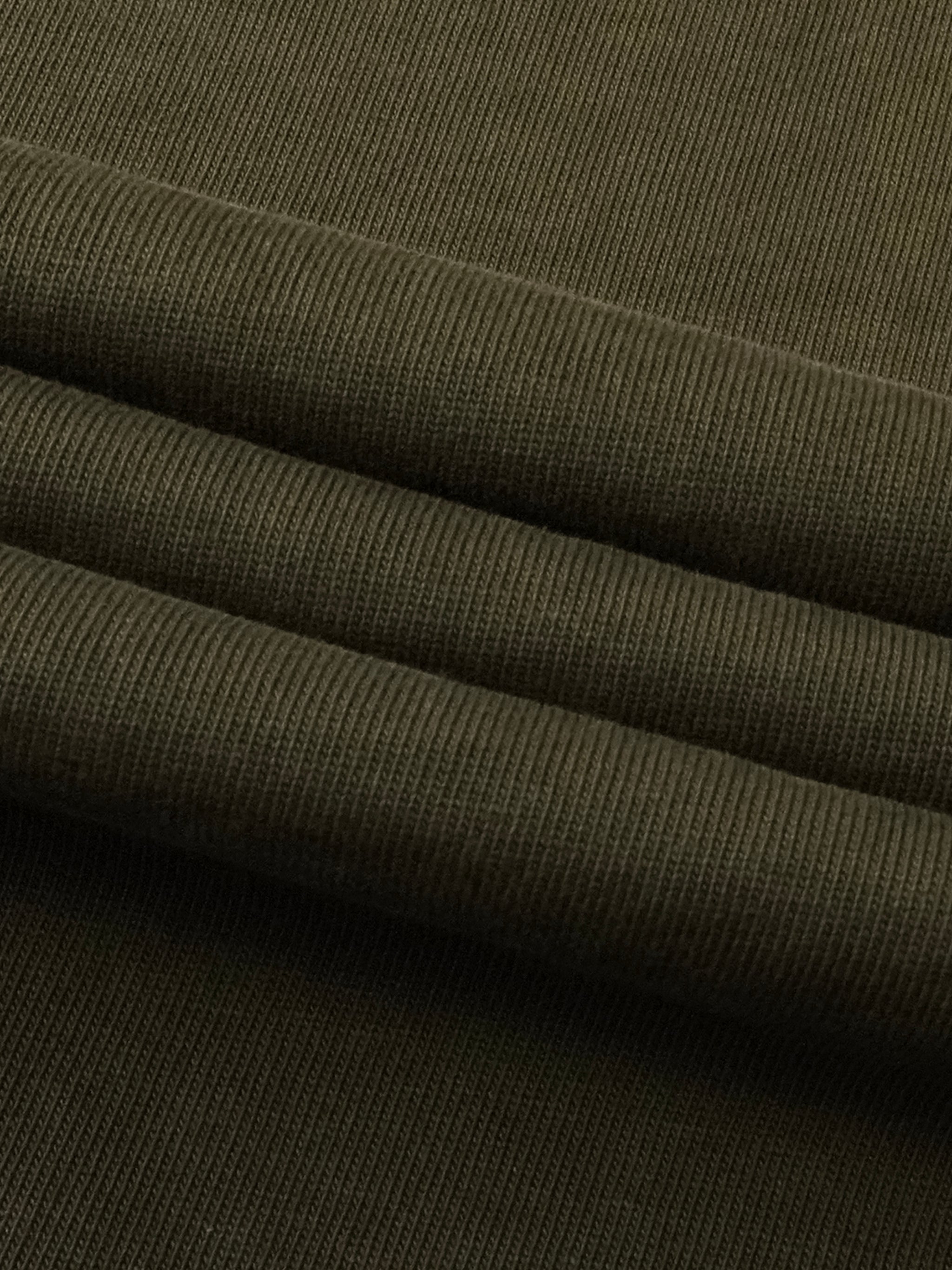 Close-up of heavyweight olive green ribbed cotton fabric, folded for streetwear apparel