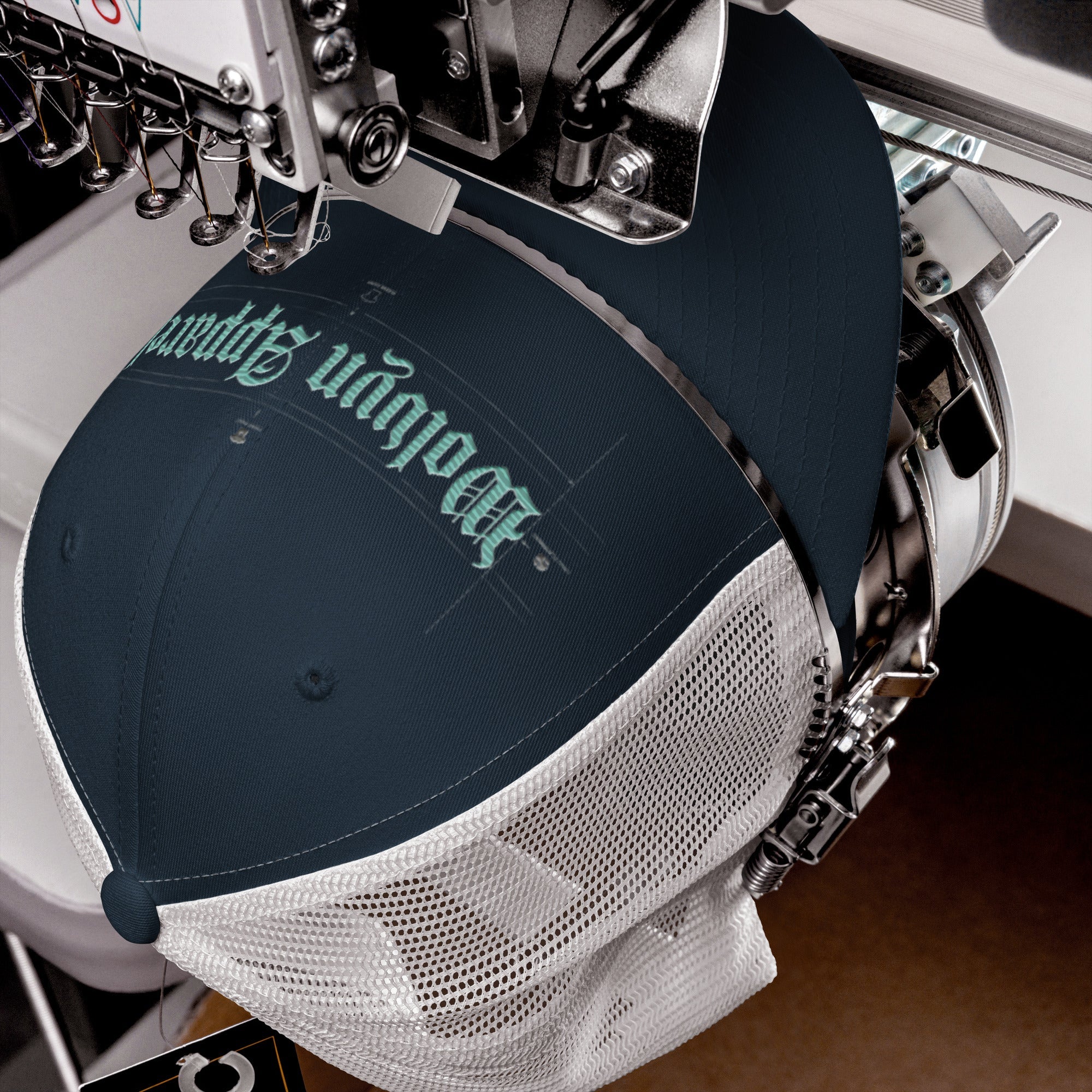 Navy and white mesh mid-profile trucker cap being embroidered with modern lettering