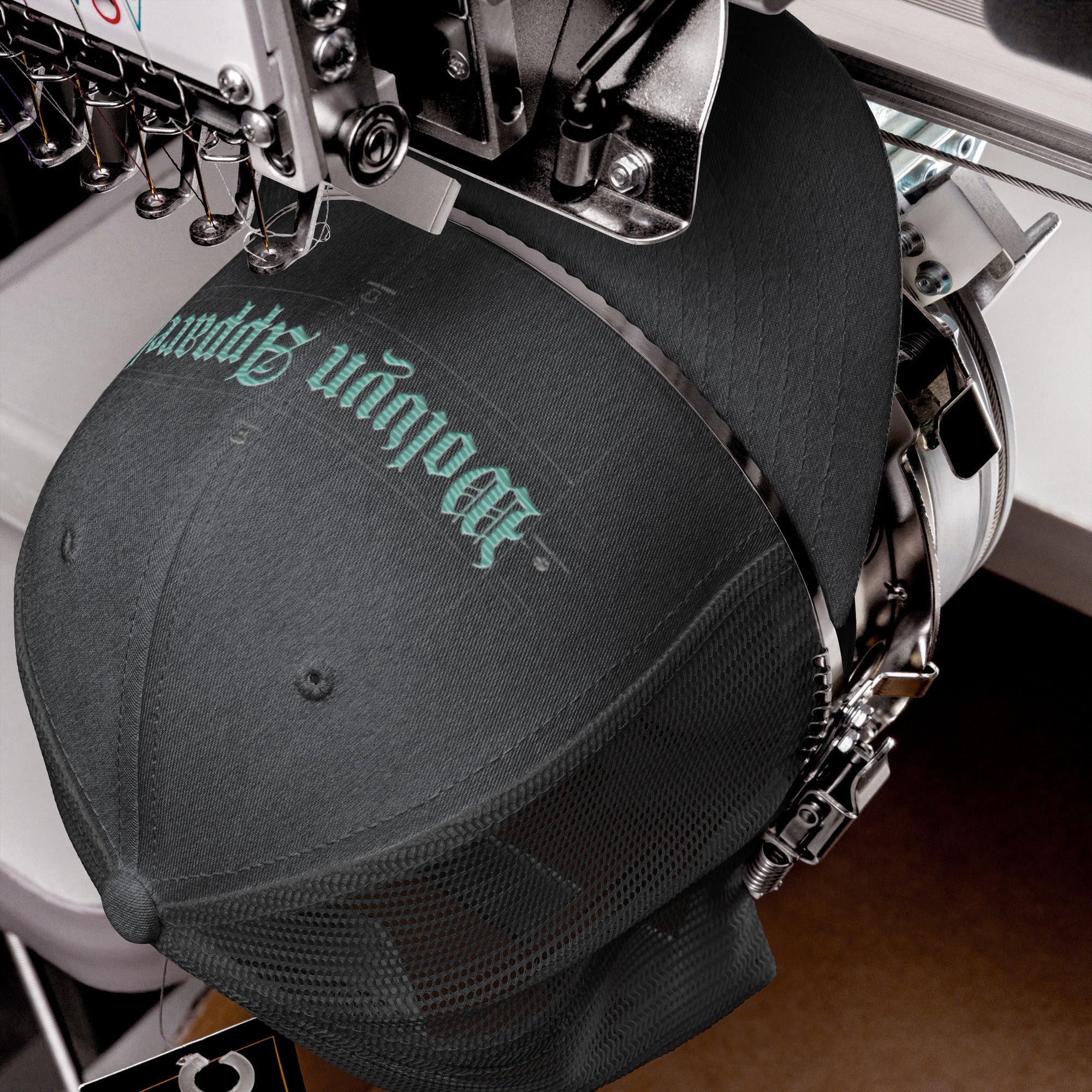 Black mid-profile trucker cap with mesh back being embroidered with gothic text