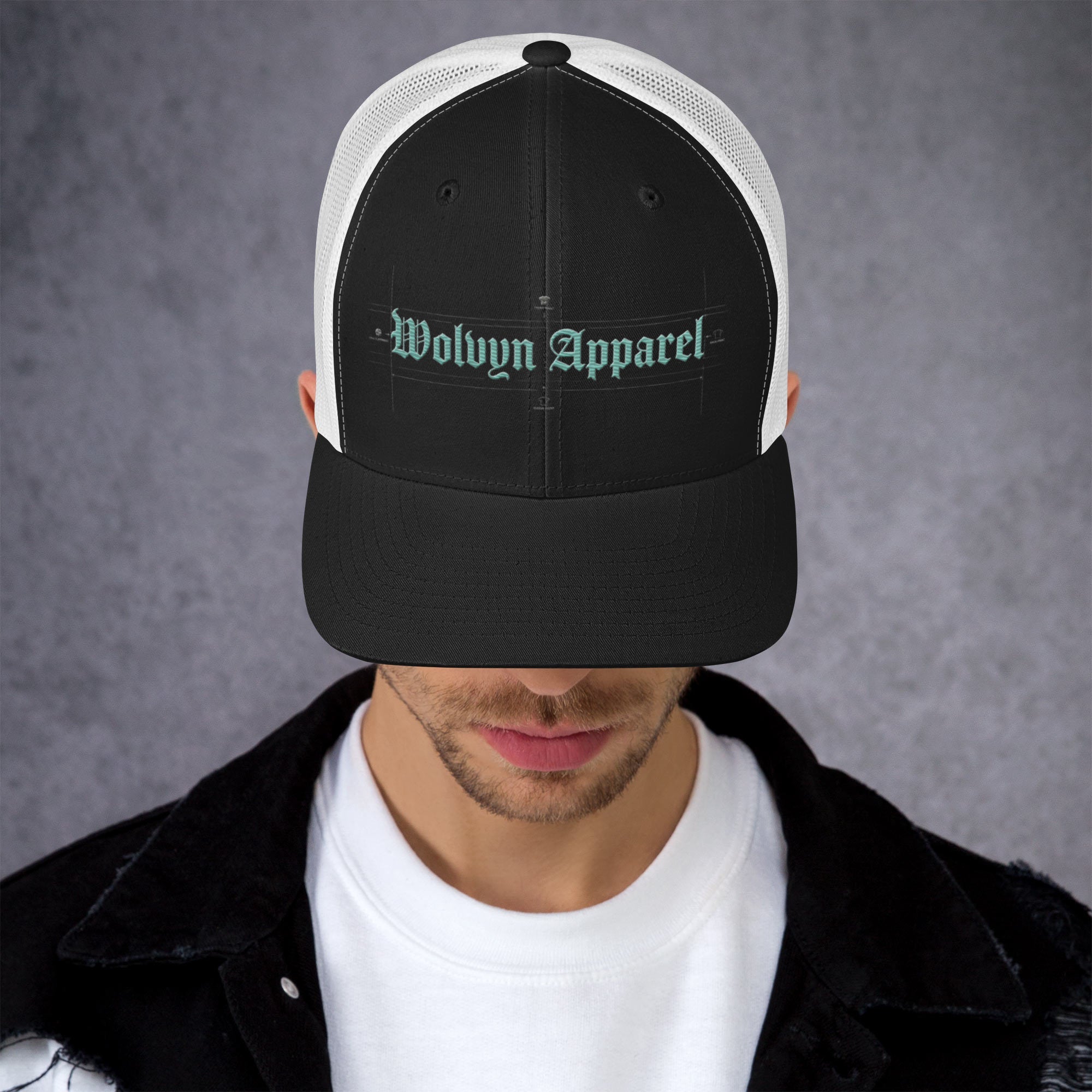 Black mid-profile embroidered trucker cap with mesh back worn by man in streetwear outfit