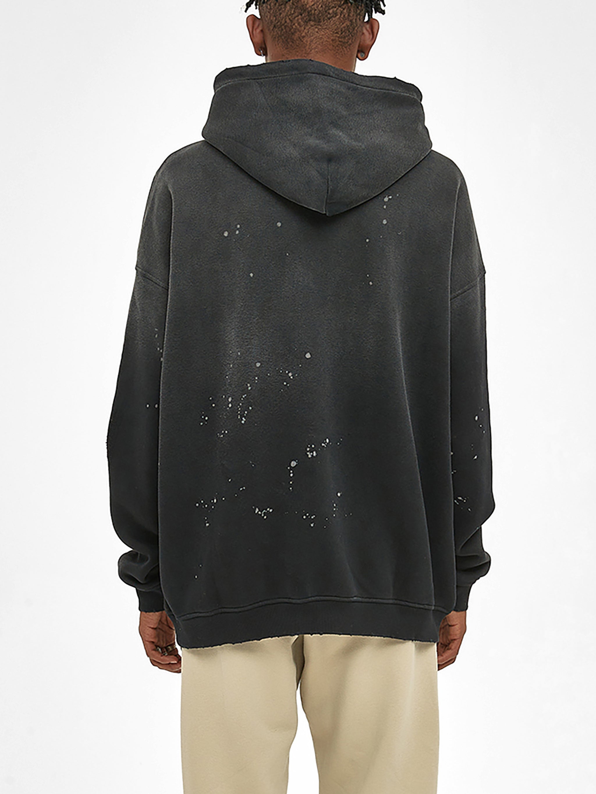 Back view of a black weathered fleece hoodie with frayed edges and paint splatter details
