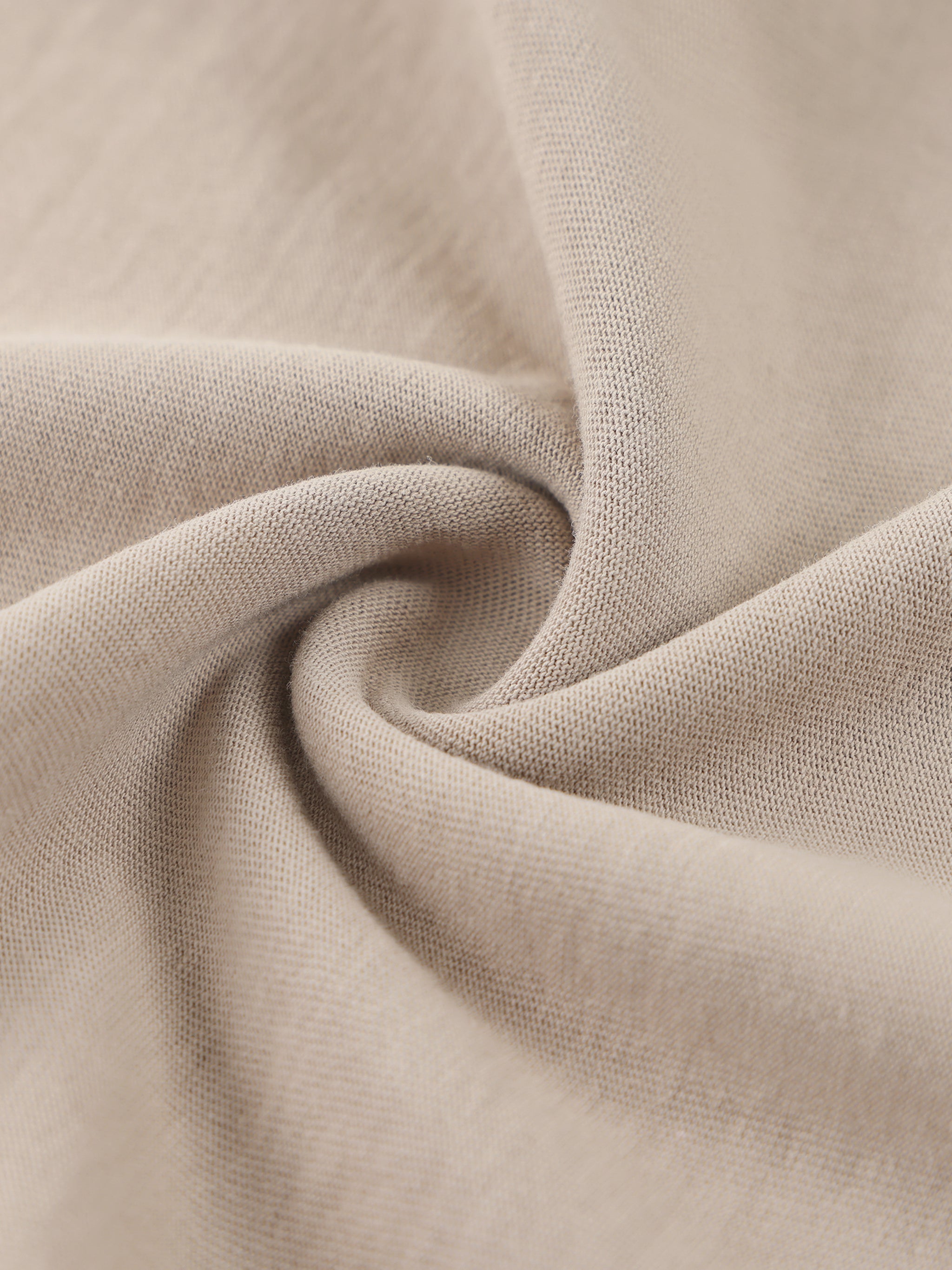 Closeup of heavyweight beige cotton fabric with raw edge texture and swirl pattern