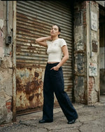 Woman wearing wide-leg black dress pants and a fitted beige top in an urban street setting.