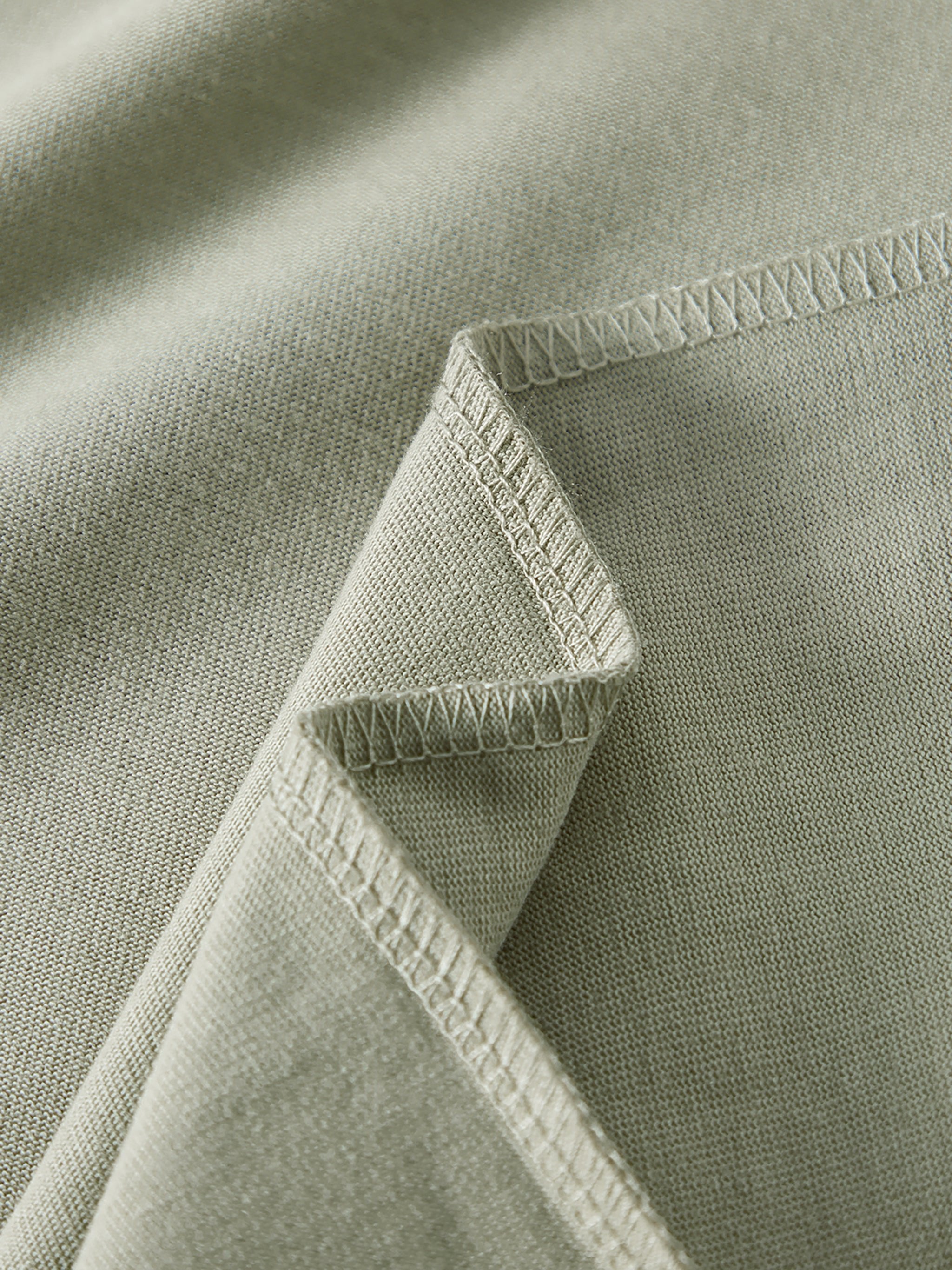 Close-up of heavyweight sage green fabric with double stitched seams