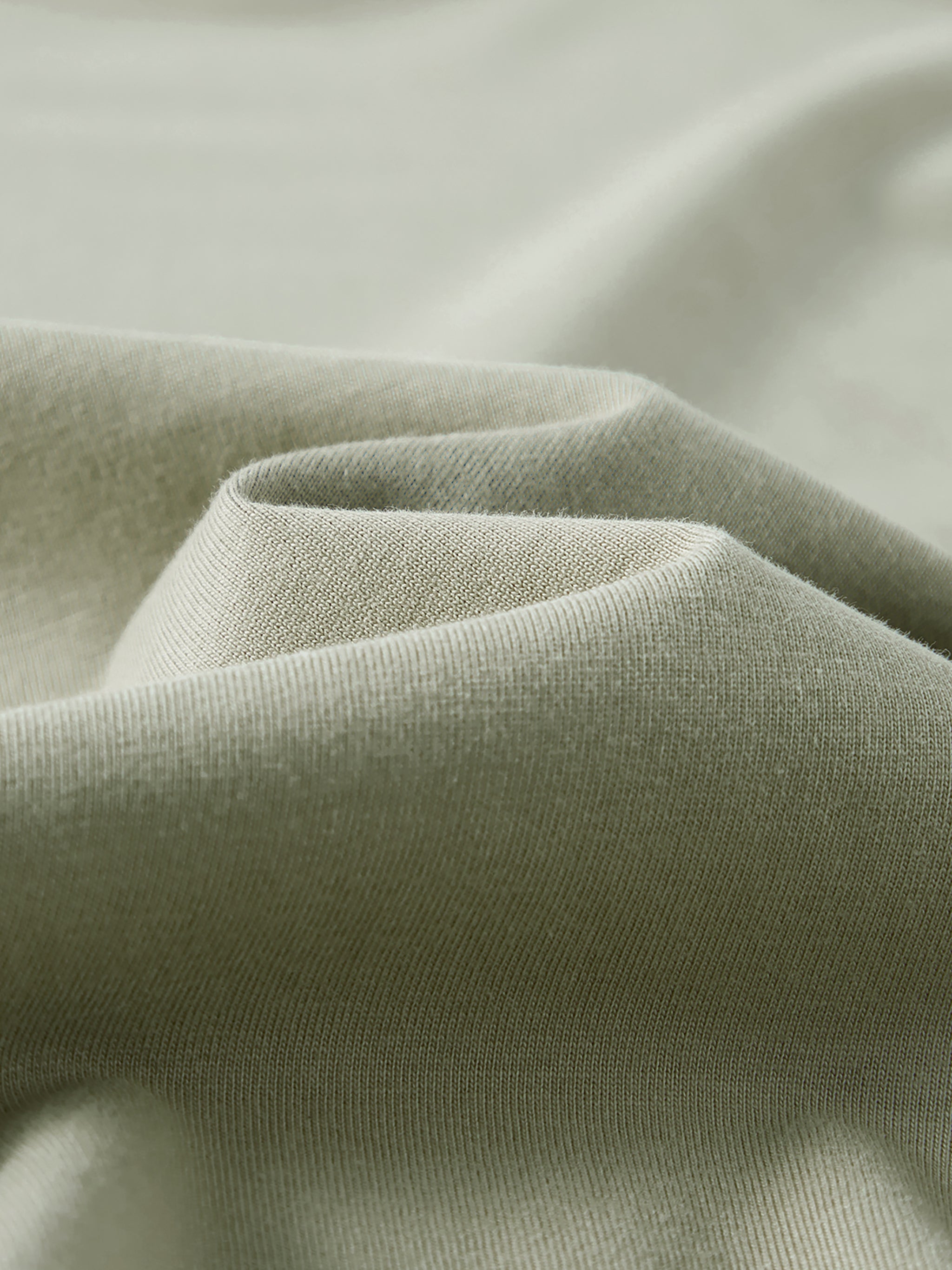 Close-up of heavyweight sage green cotton fabric texture with soft folds