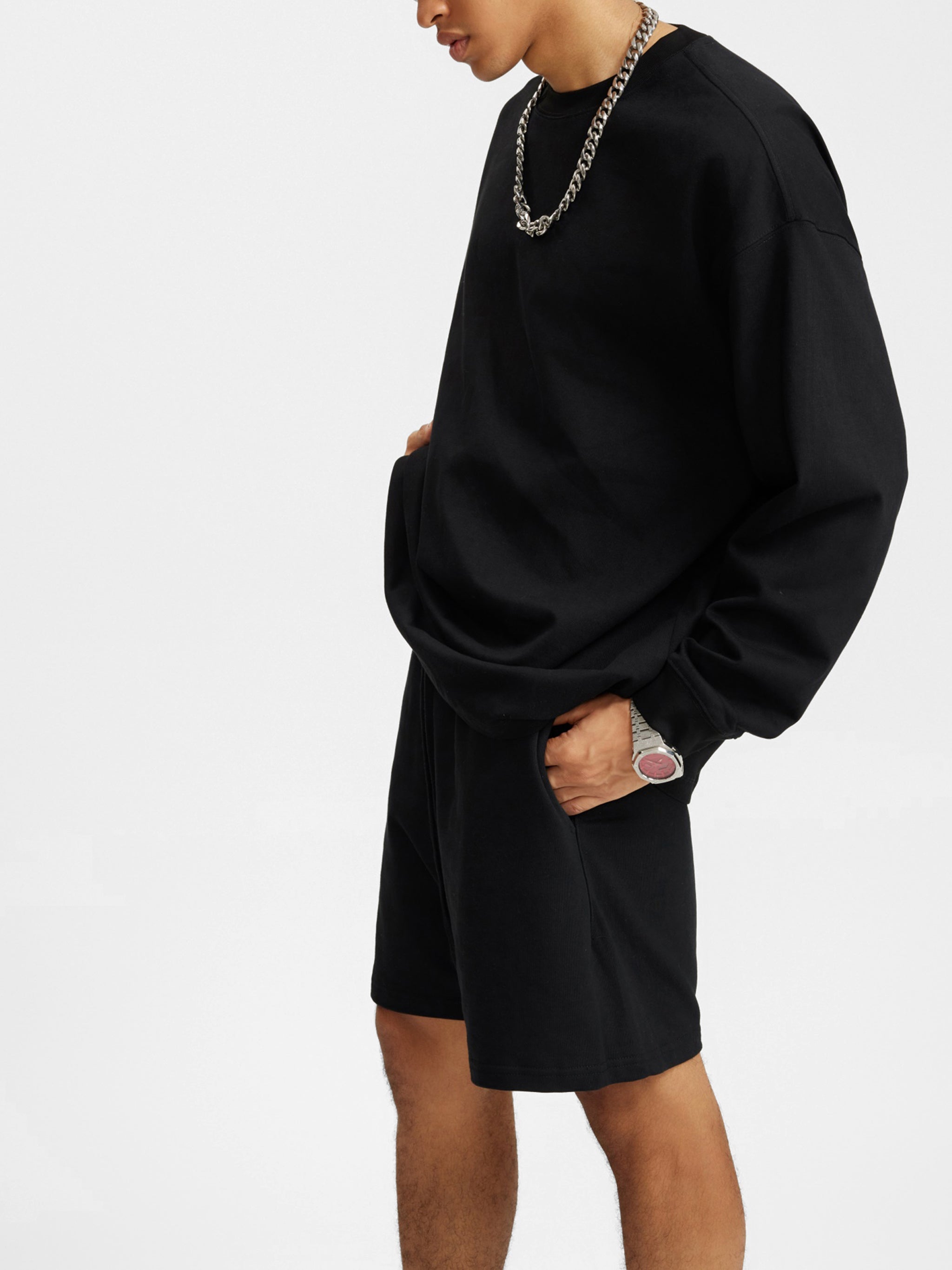 Man wearing oversized black long sleeve t-shirt and shorts with chain necklace