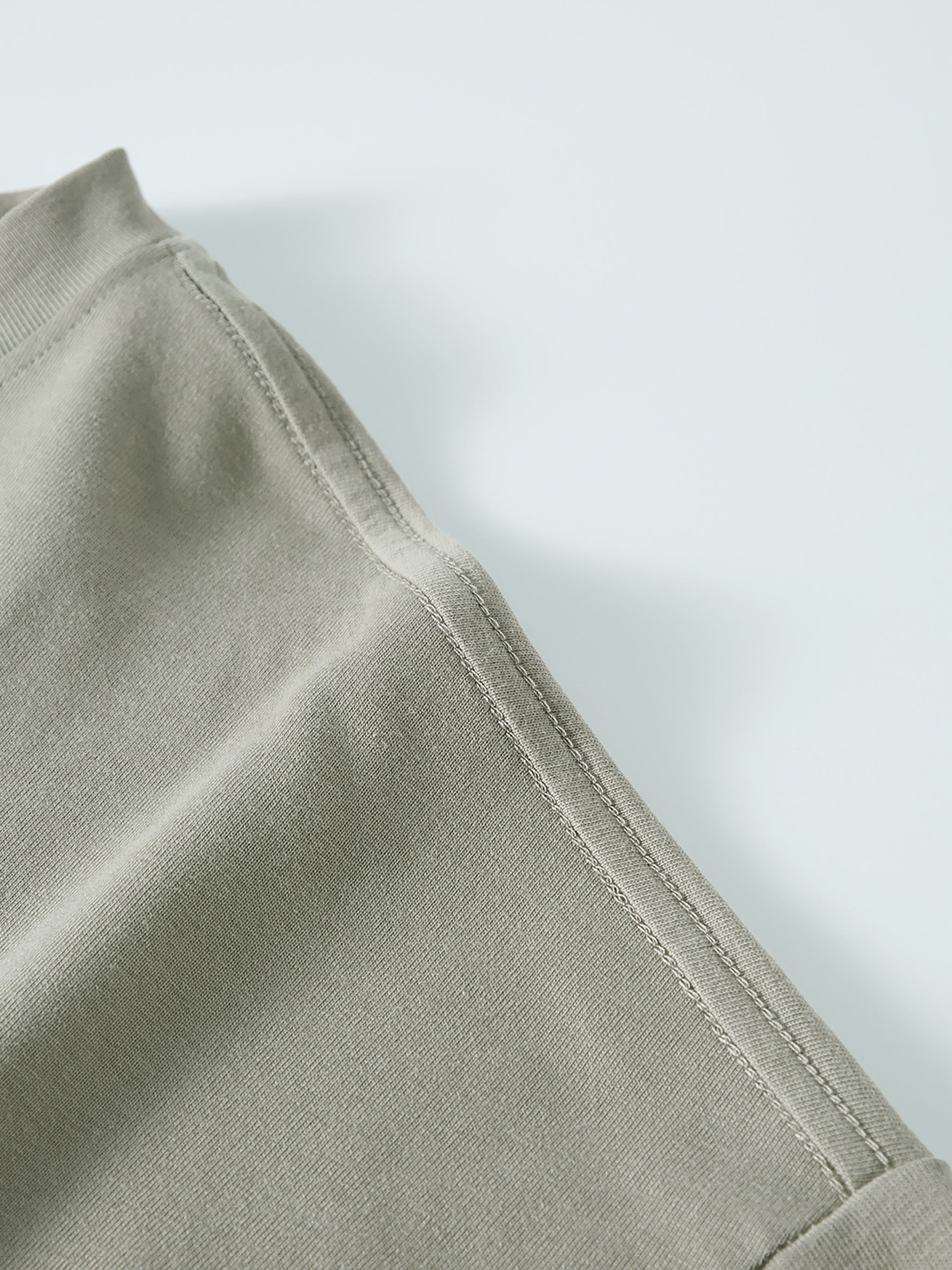 Close-up of beige heavyweight long sleeve t-shirt shoulder seam on flat background