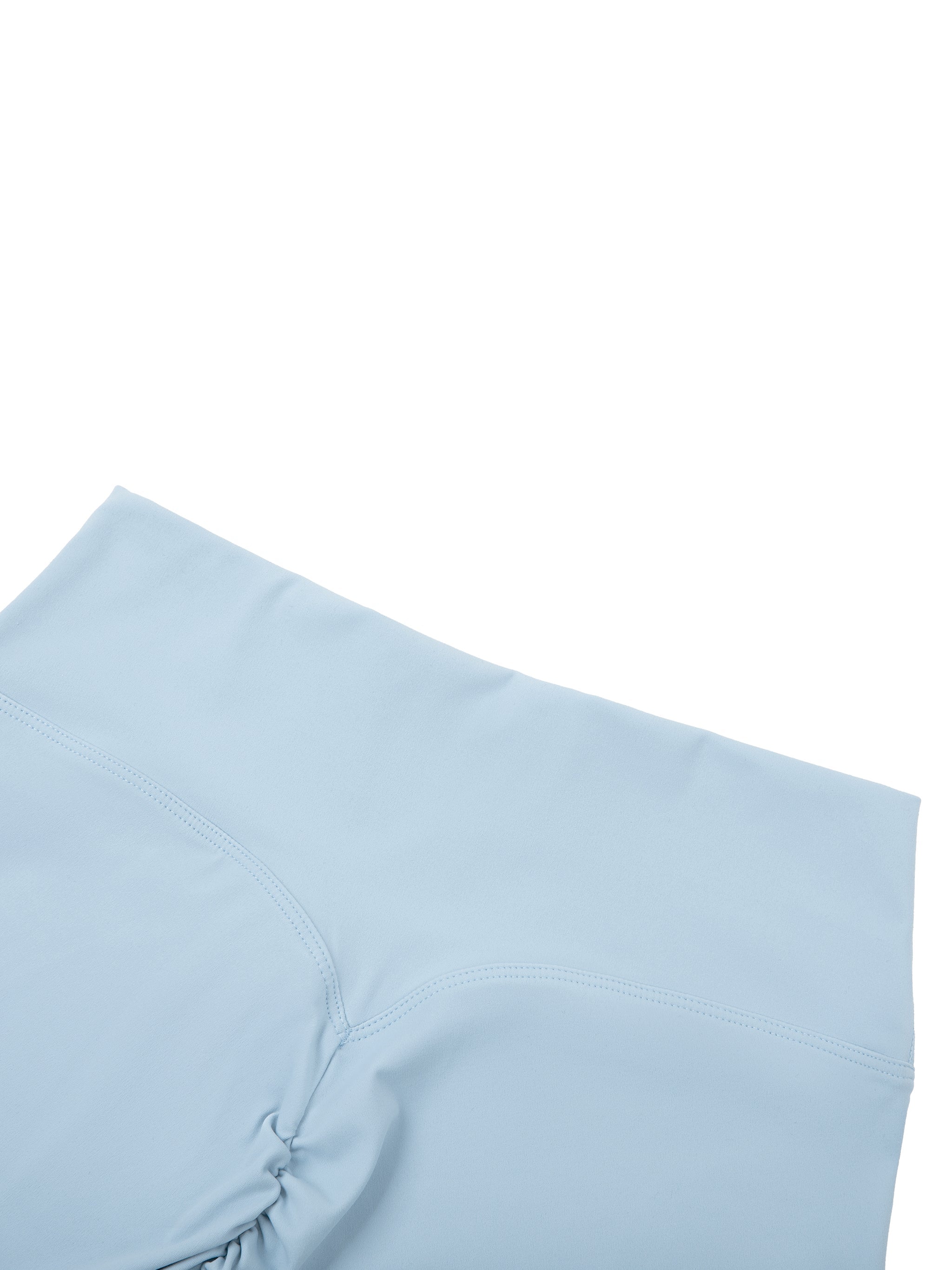 Light blue high-waisted biker shorts with ruched seam detail, laid flat