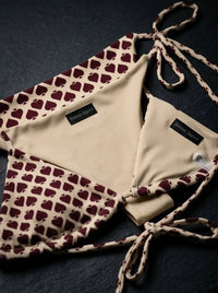 Beige and burgundy spade print string bikini set with tie straps on a dark background