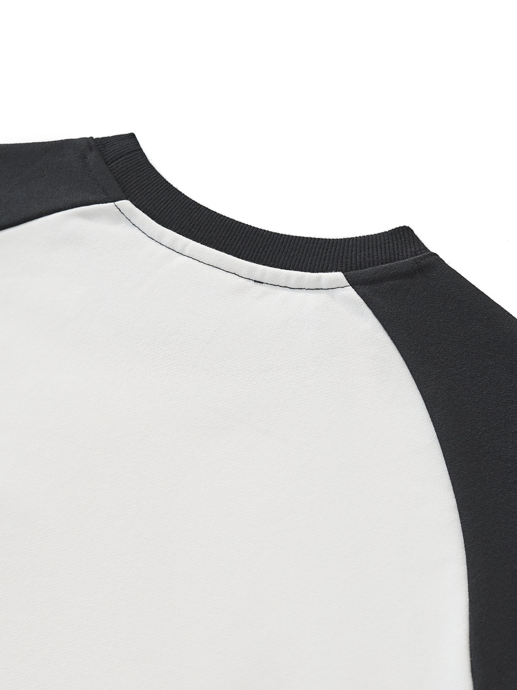 Closeup of black and white color block raglan crop sweatshirt with raw hem detail.