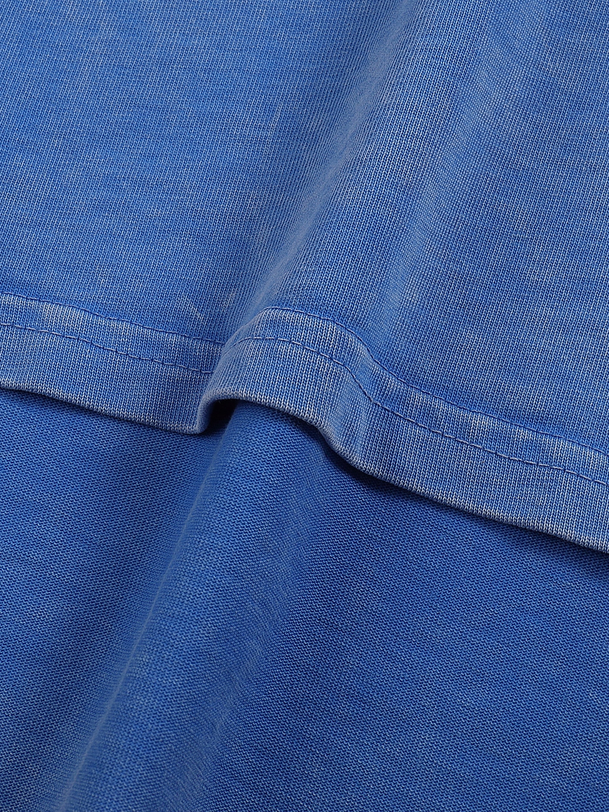 Close-up of blue snow-washed oversized cotton t-shirt hem with textured fabric detail