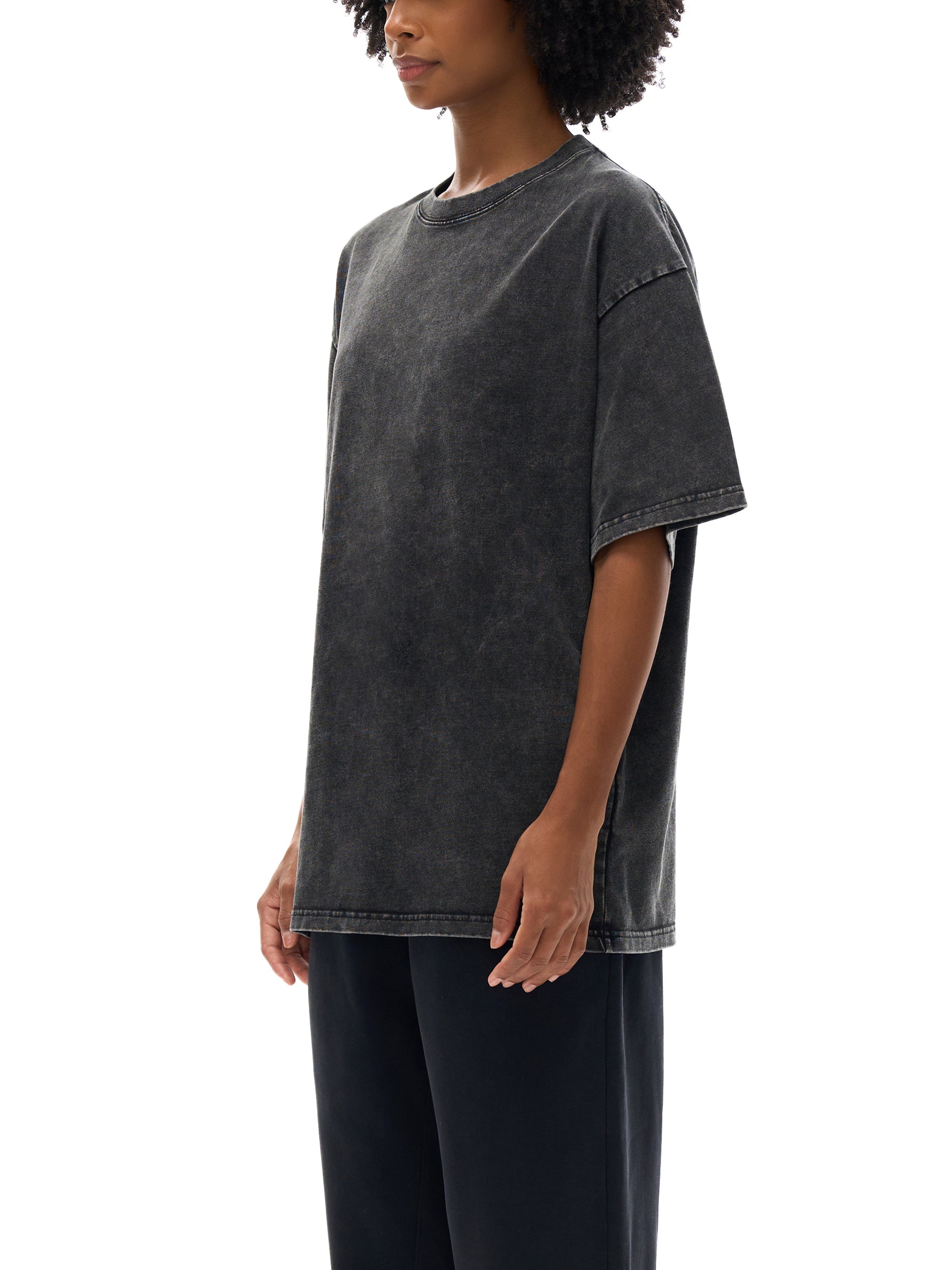 Woman wearing black snow washed oversized cotton t-shirt, side view, plain white background