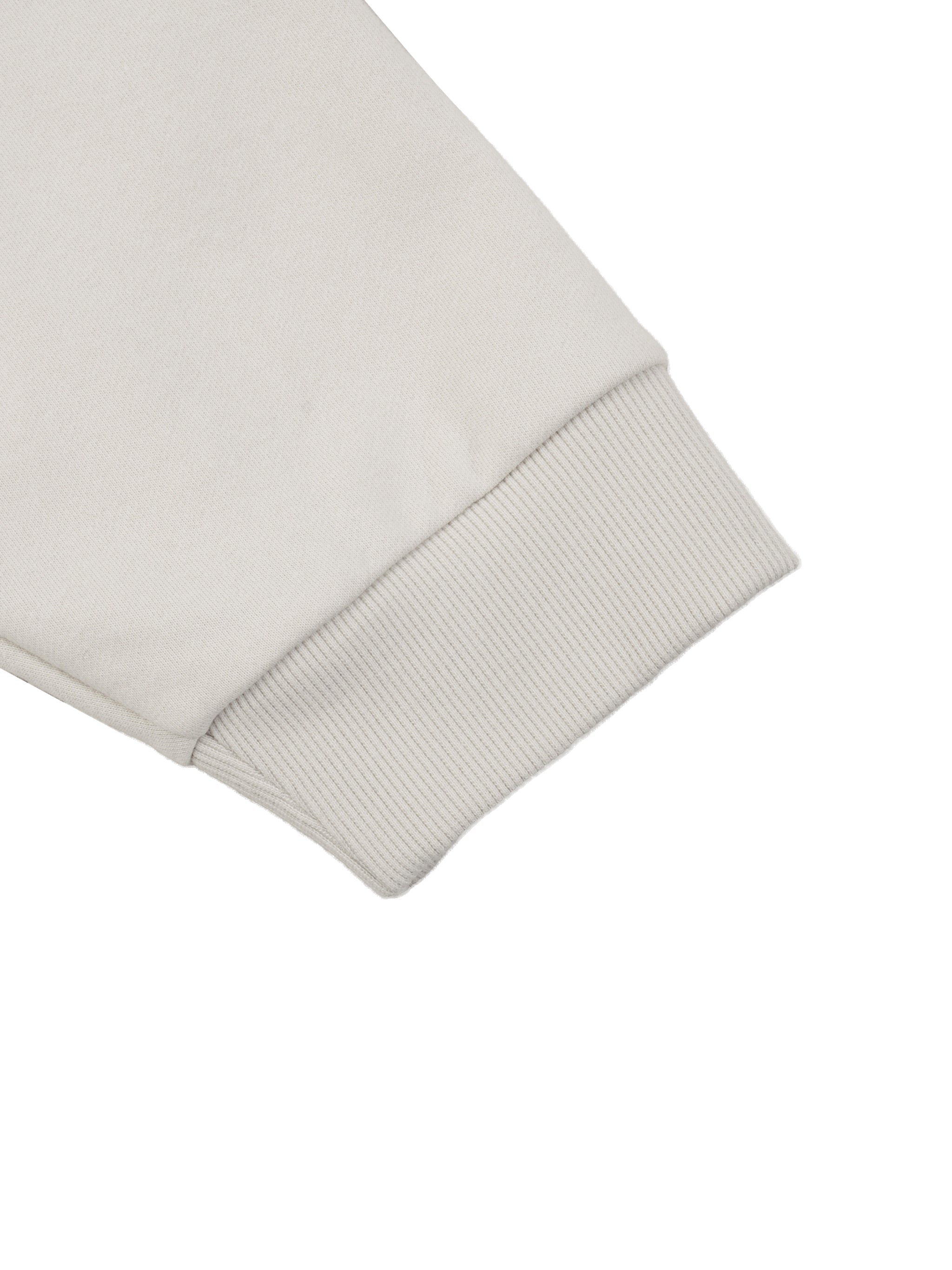 Close-up of beige jacket raglan sleeve with ribbed cuff on white background