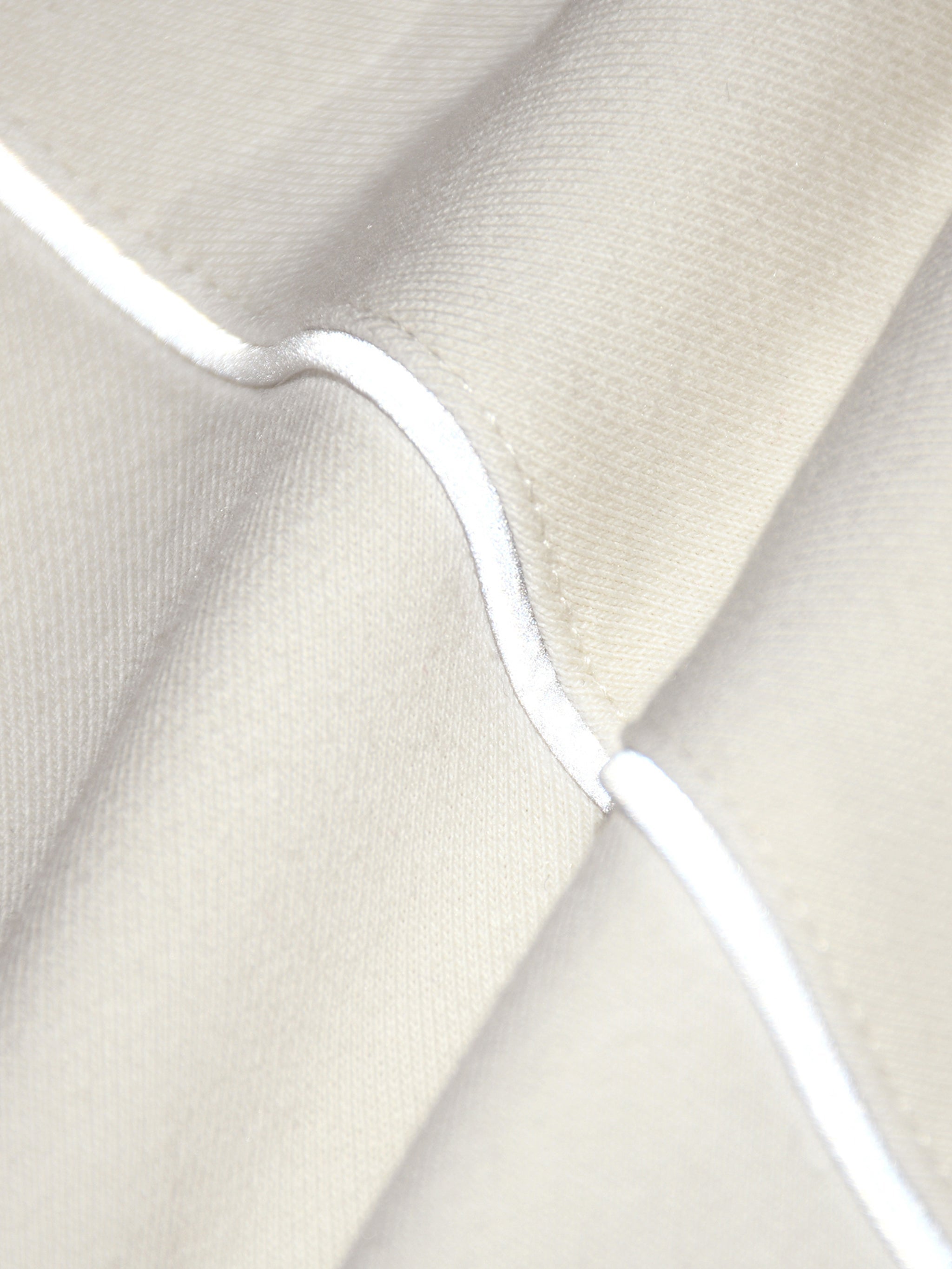 Close-up of cream fabric with reflective striped raglan seam detail on a jacket