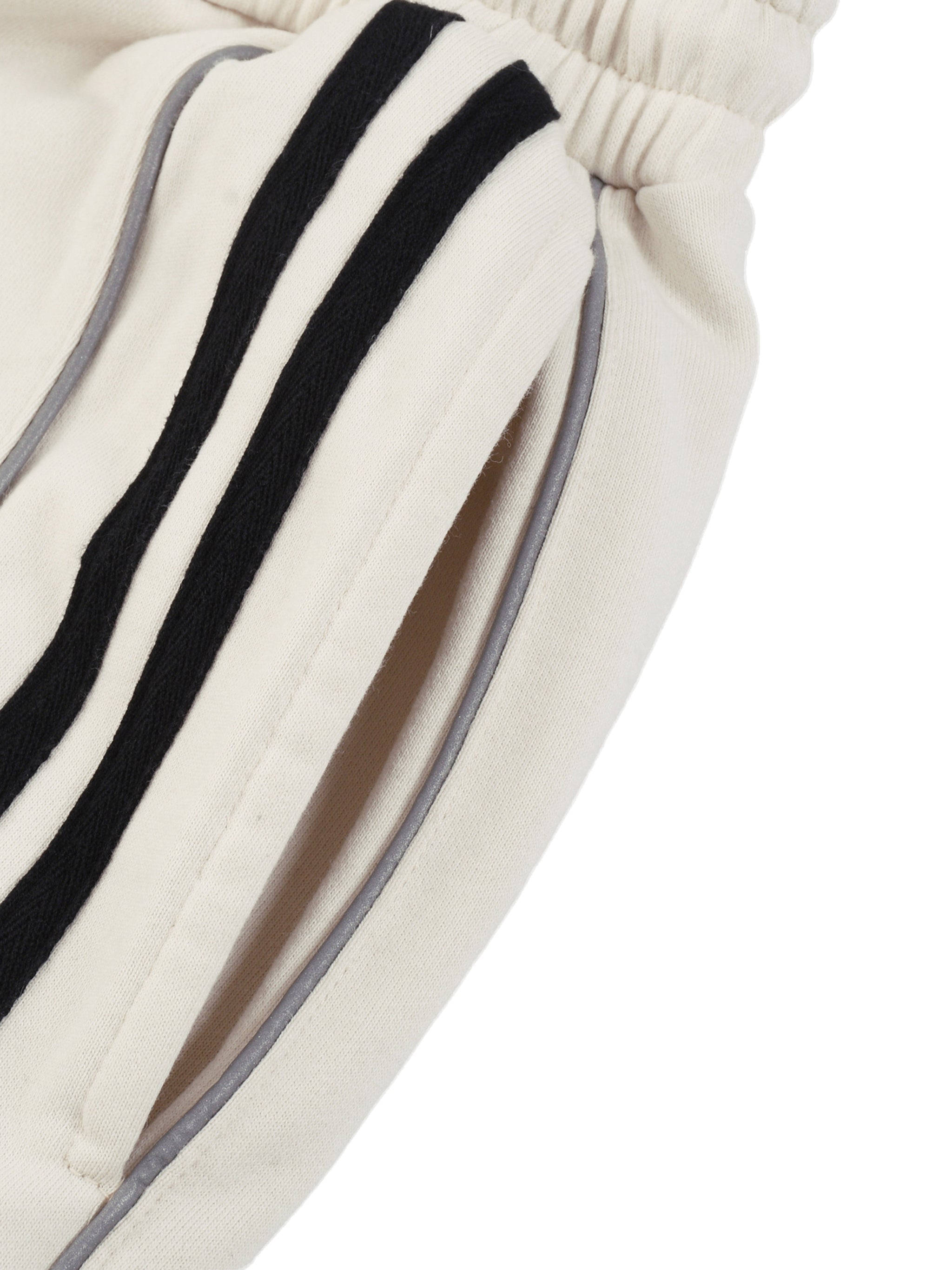 Close-up of cream sweatpants with black stripes and elastic waistband, straight leg style