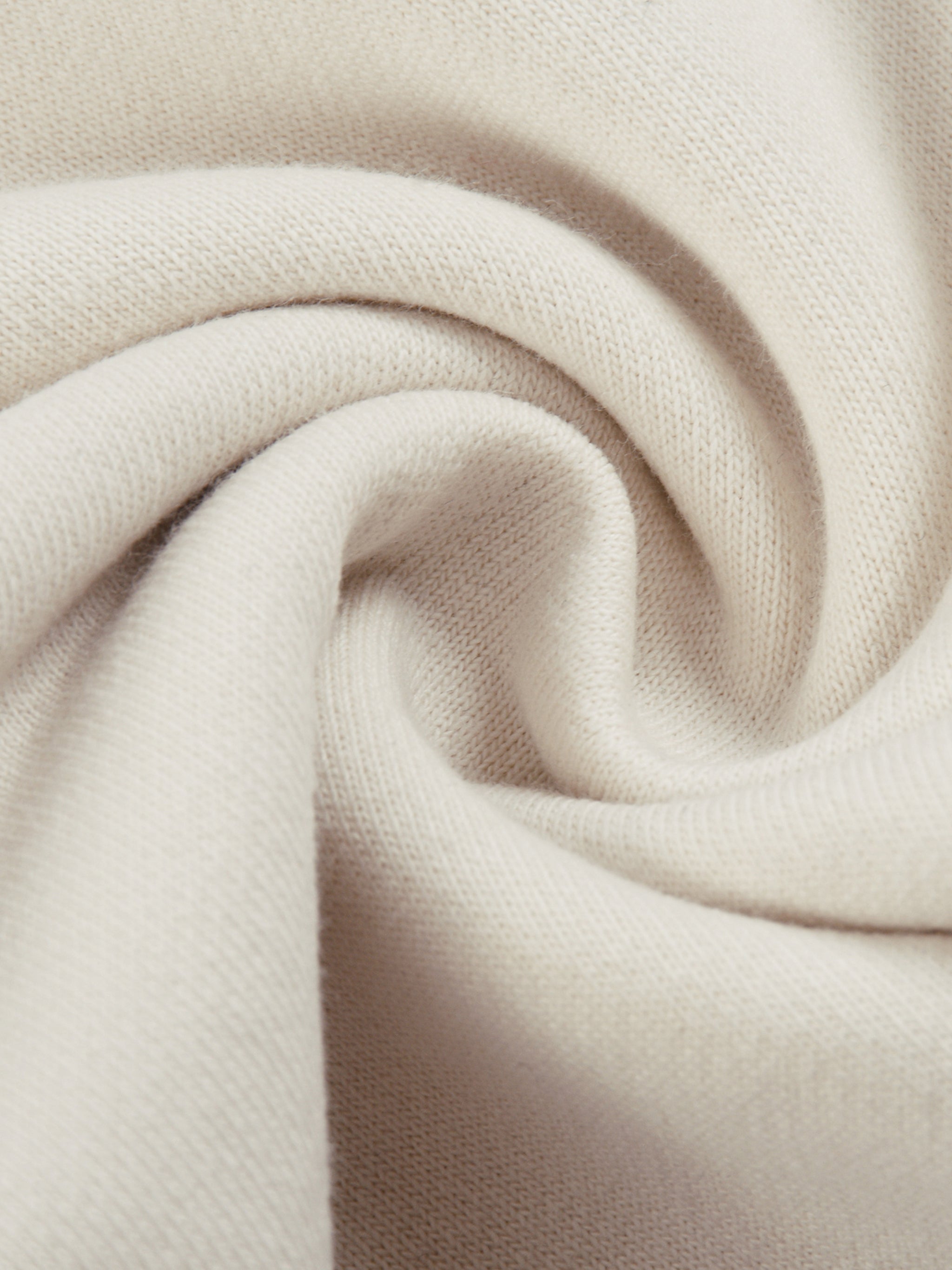 Close-up of soft beige heavyweight knit fabric with visible texture, ideal for sweatpants.