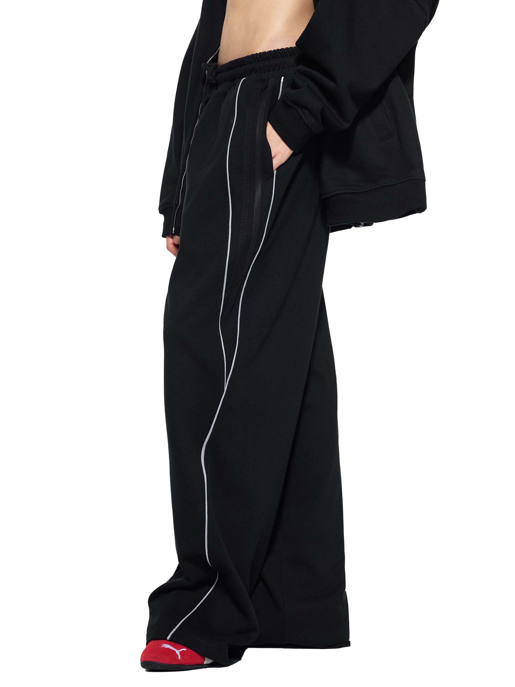 Black straight leg sweatpants with white reflective stripes and elastic waistband, streetwear style.
