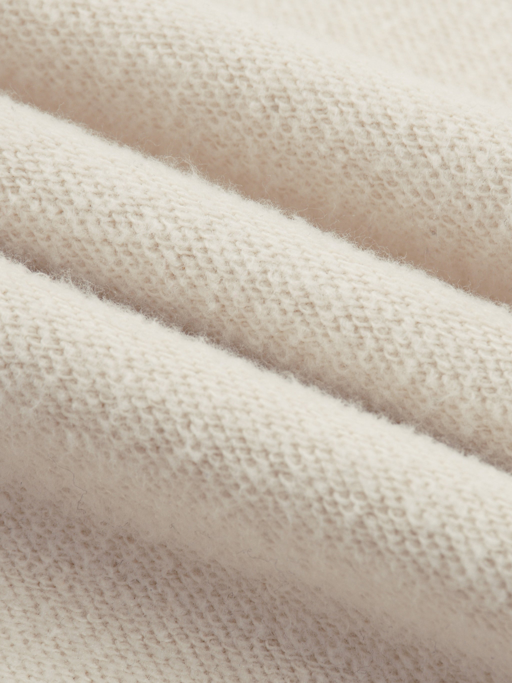 Close-up of soft cream-colored heavyweight knit fabric with textured surface