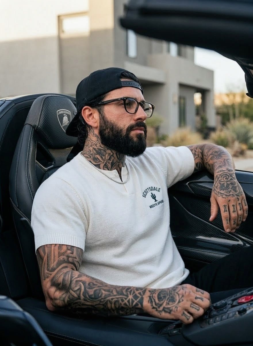 Tattooed man in white Scottsdale cotton knit Henley t-shirt sitting in a convertible car