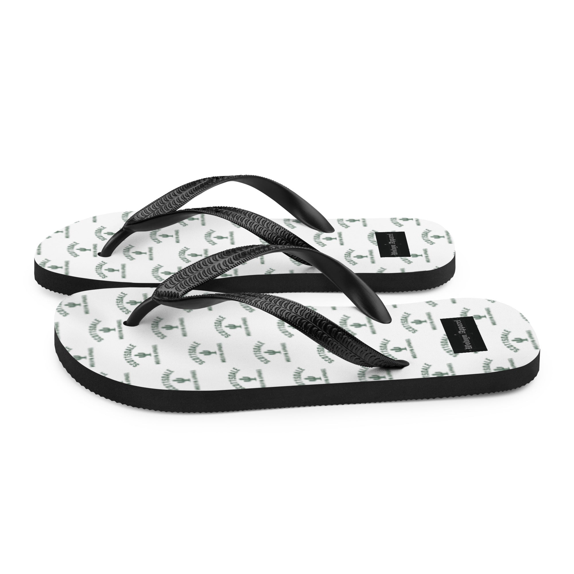White flip flops with black straps and repeating green graphic pattern on sole