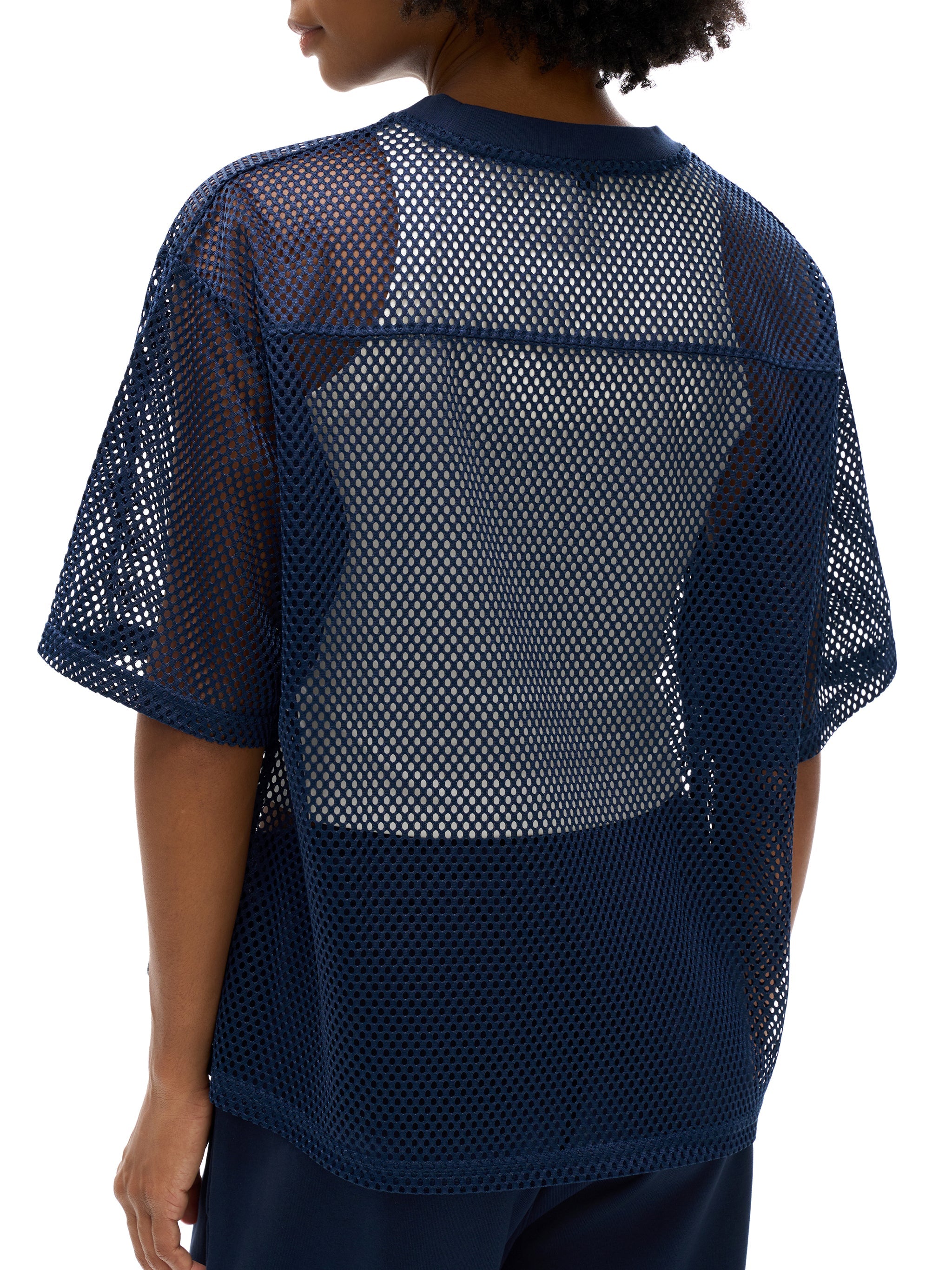Back view of a person wearing a navy blue see-through mesh boxy net t-shirt