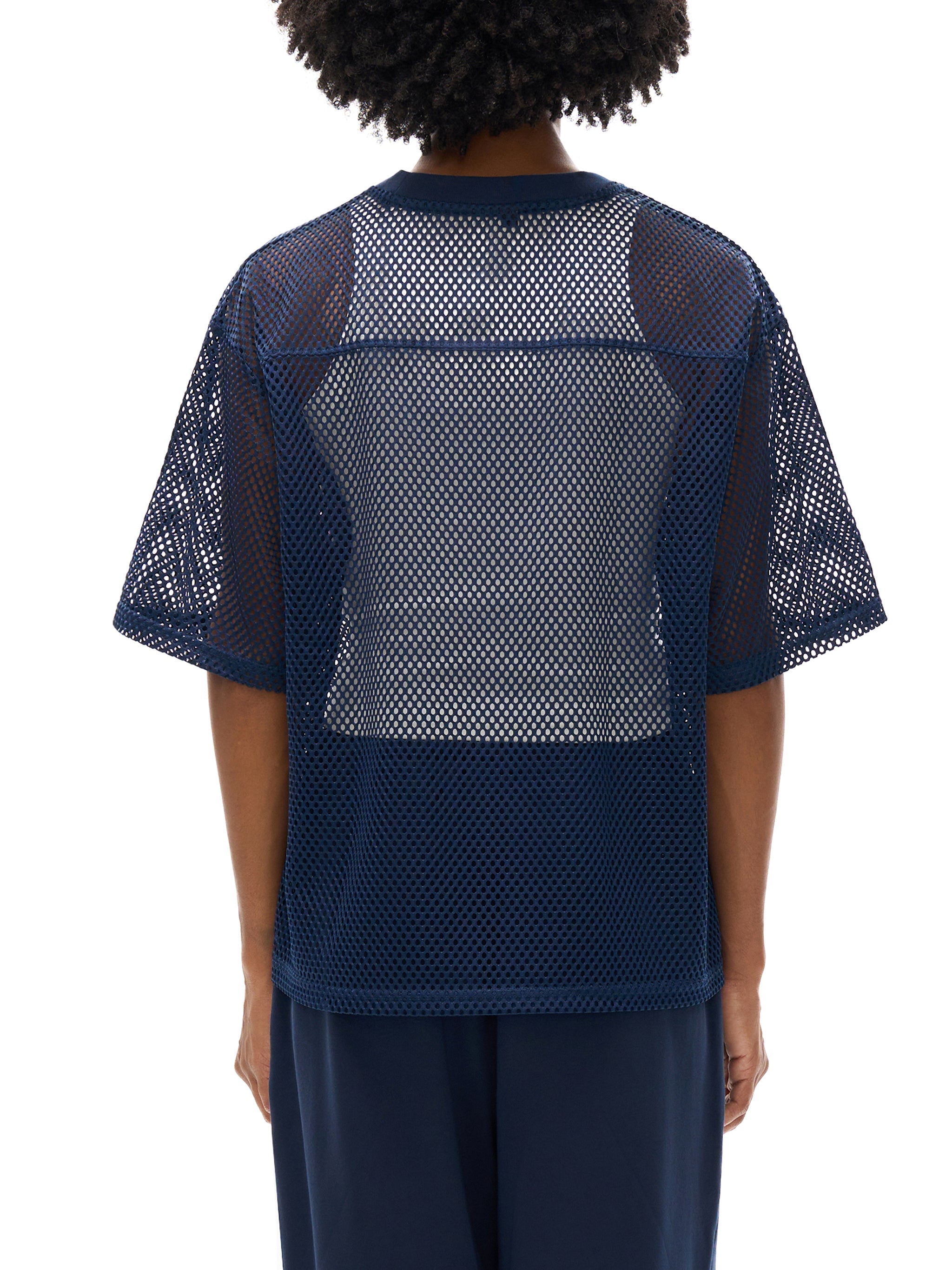 Back view of person wearing a navy blue see-through boxy mesh net t-shirt