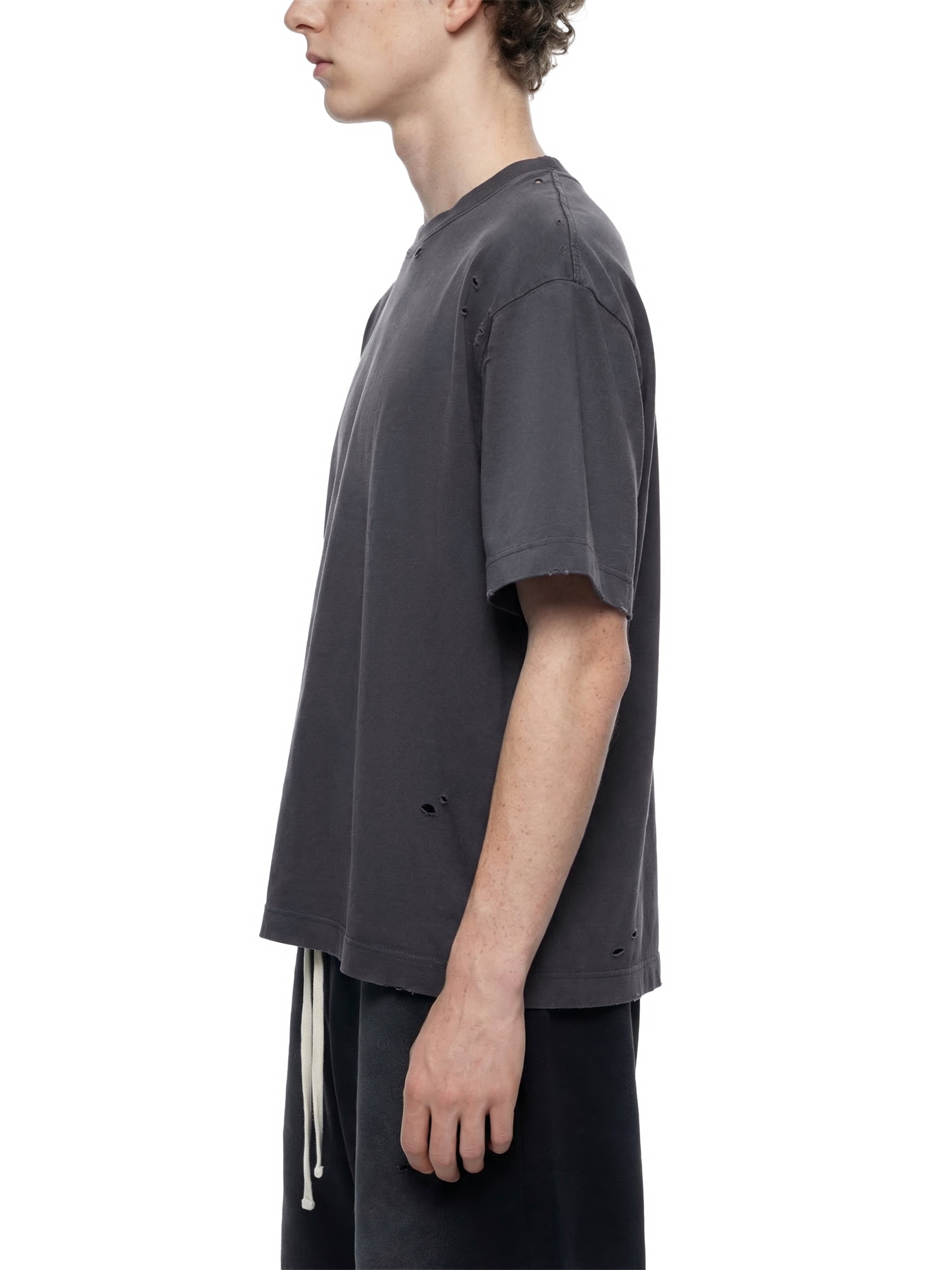 Man wearing vintage washed, oversized distressed black t-shirt, side profile view