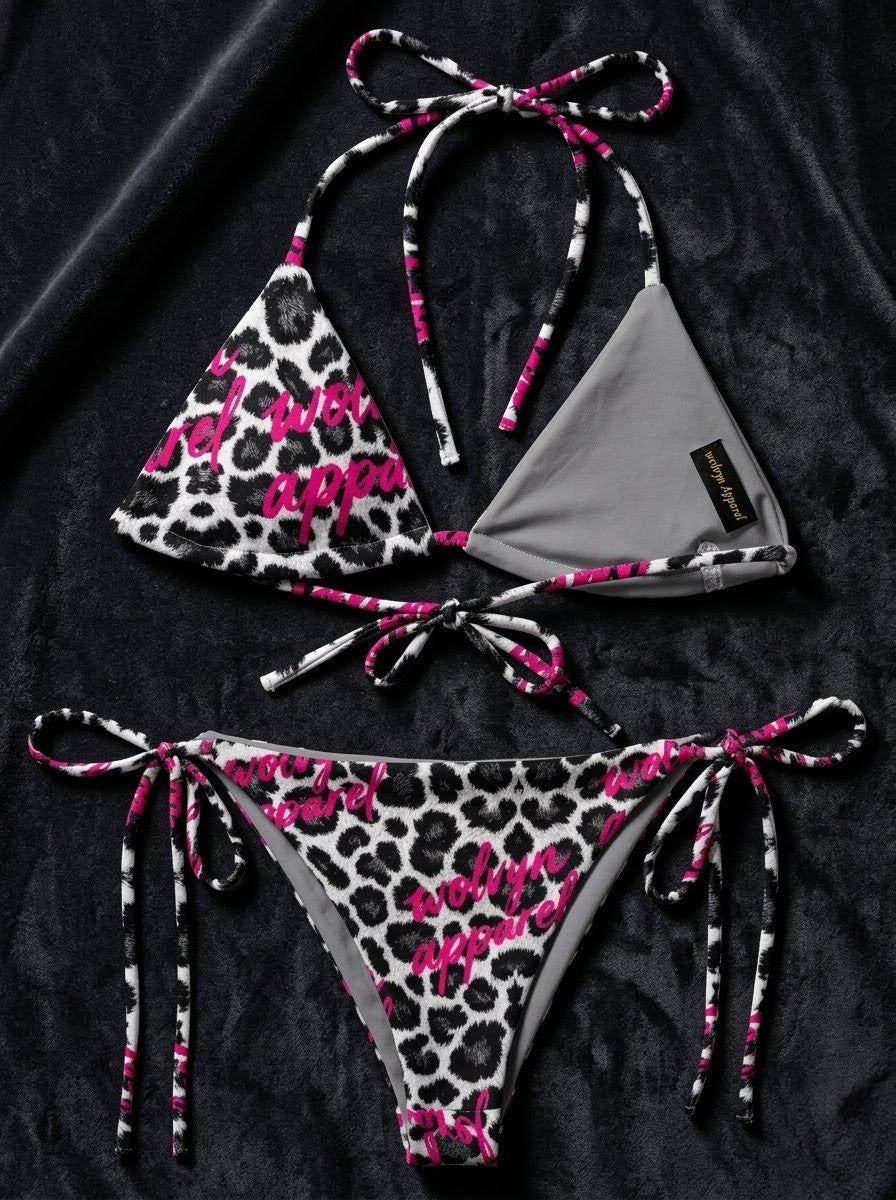 Snow leopard print string bikini with pink logo accents on black fabric background