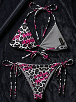Snow leopard print string bikini with pink logo accents on black fabric background