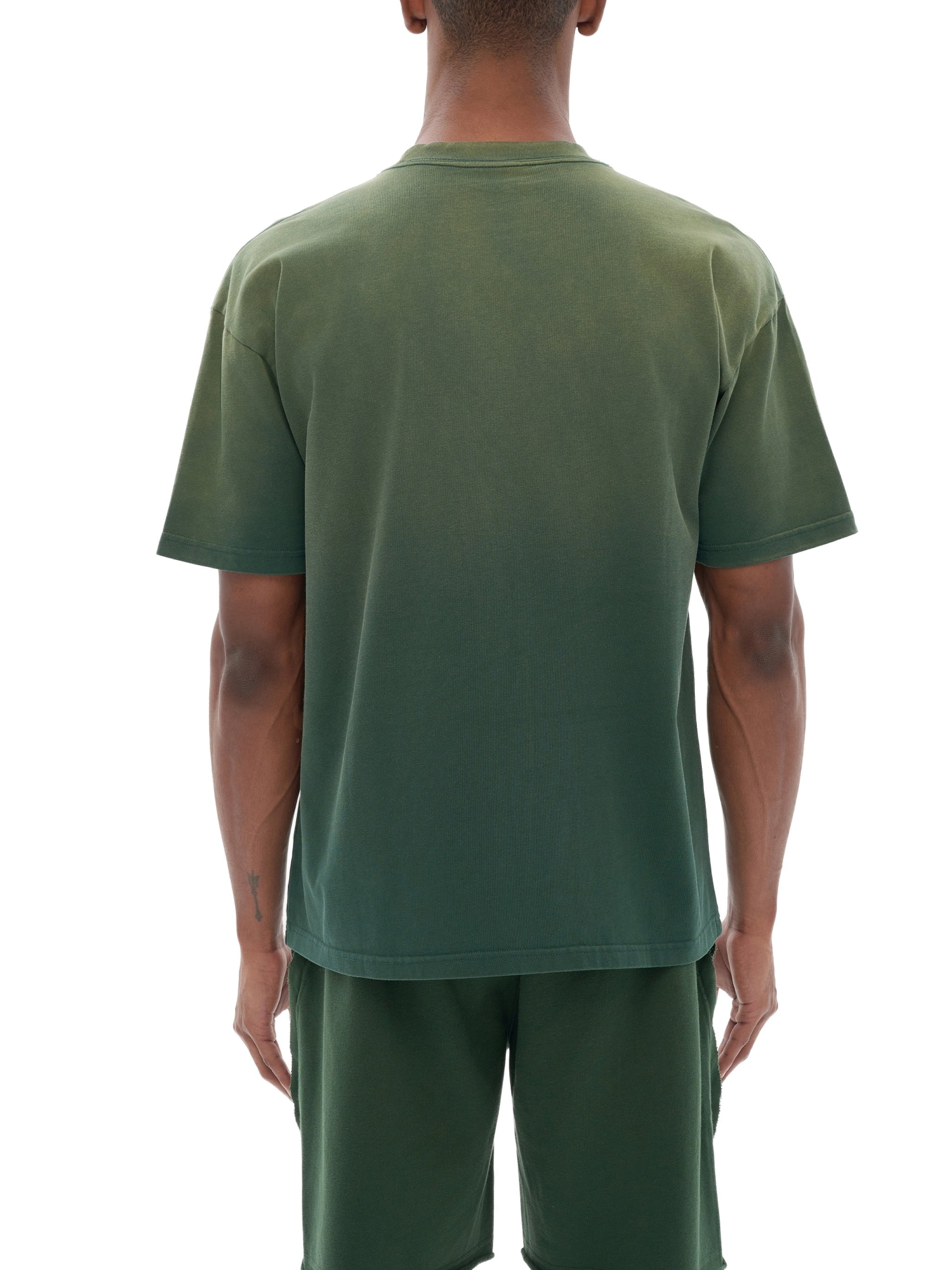 Back view of a man wearing a green gradient washed t-shirt and matching shorts