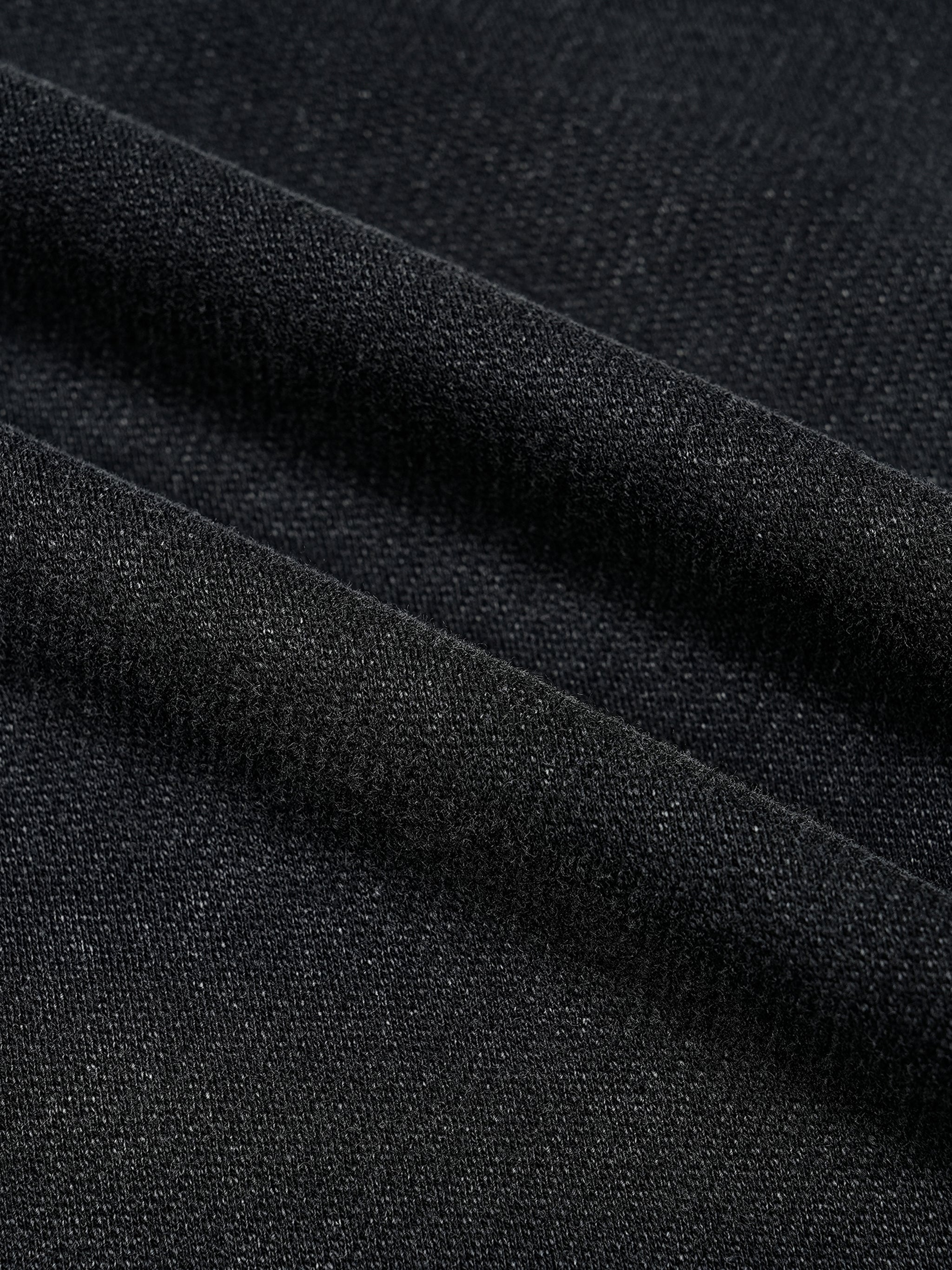 Close-up of heavyweight black vintage wash t-shirt fabric with soft texture and distressed hem
