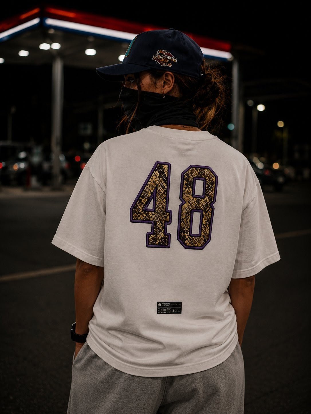 Person wearing a white heavyweight t-shirt with bold '48' print and streetwear style at night