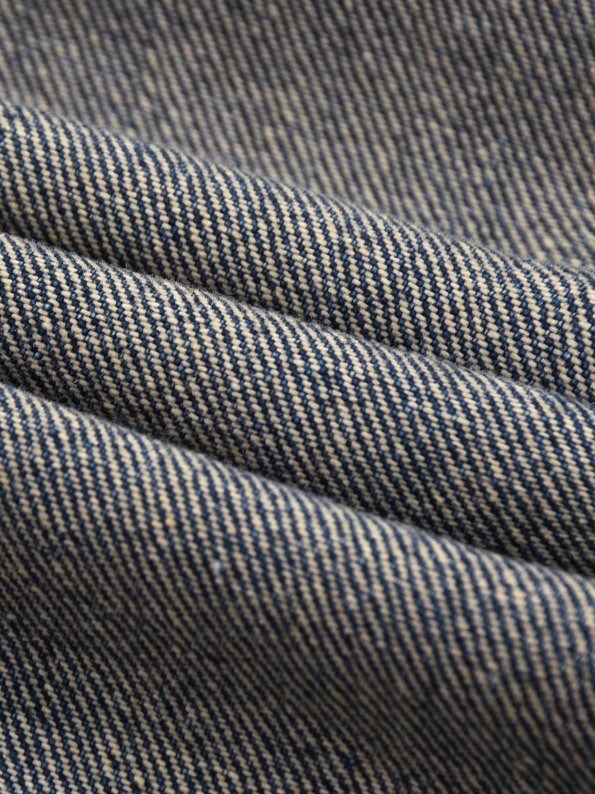 Close-up of vintage wash blue denim fabric with textured weave and folds.