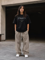 Woman in casual streetwear, black graphic t-shirt and beige sweatpants, urban setting