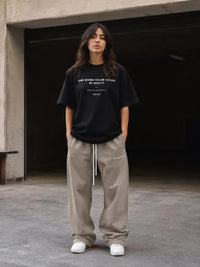 Woman in casual streetwear, black graphic t-shirt and beige sweatpants, urban setting