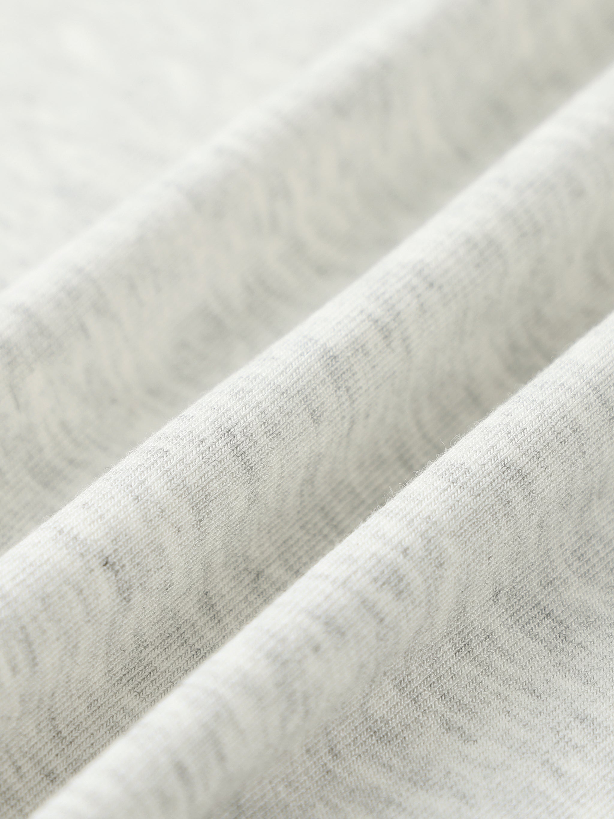 Close-up of soft, heathered white knit fabric with visible texture folds