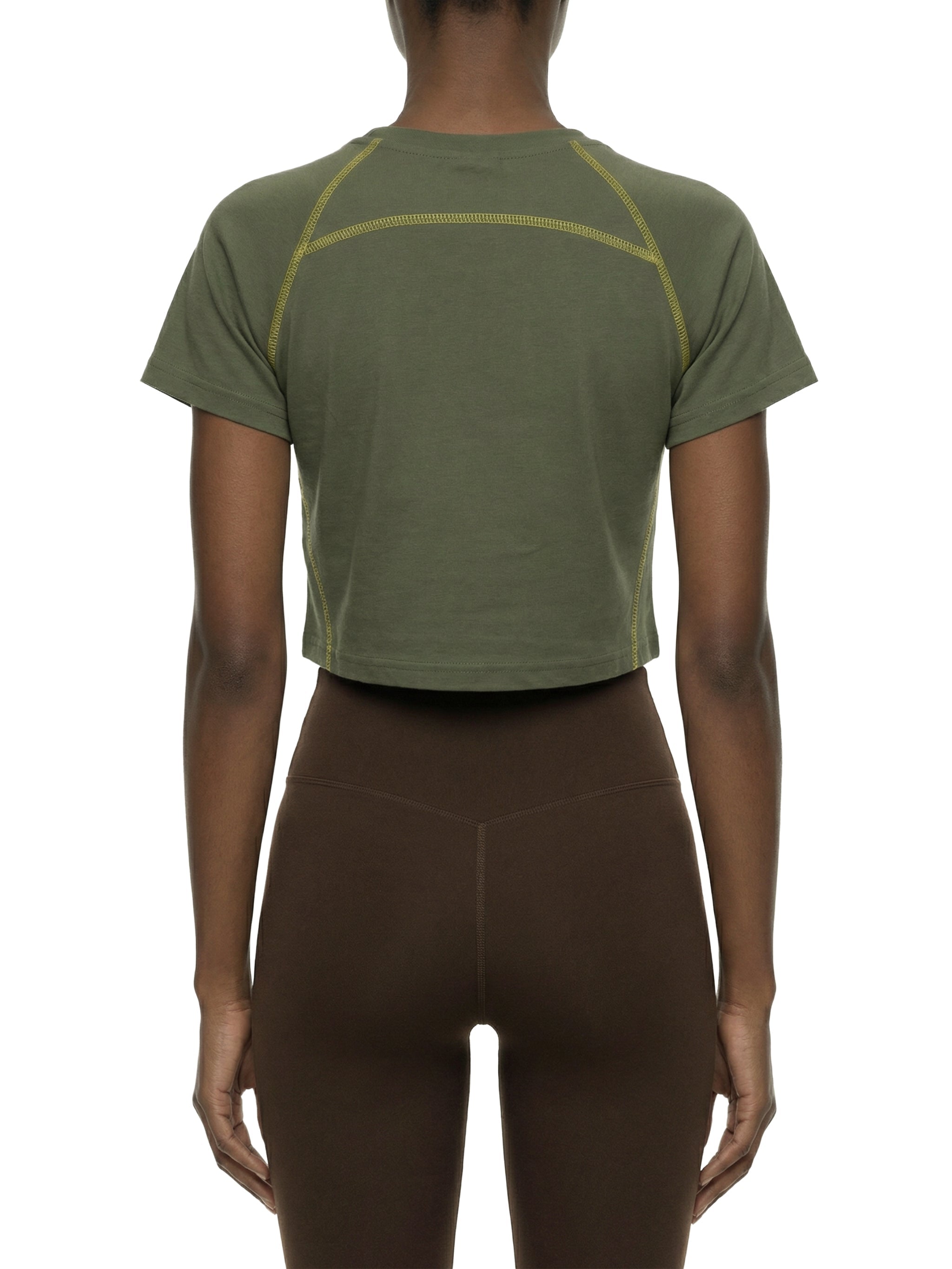 Back view of woman wearing olive green contrast stitch raglan crop t-shirt and brown leggings