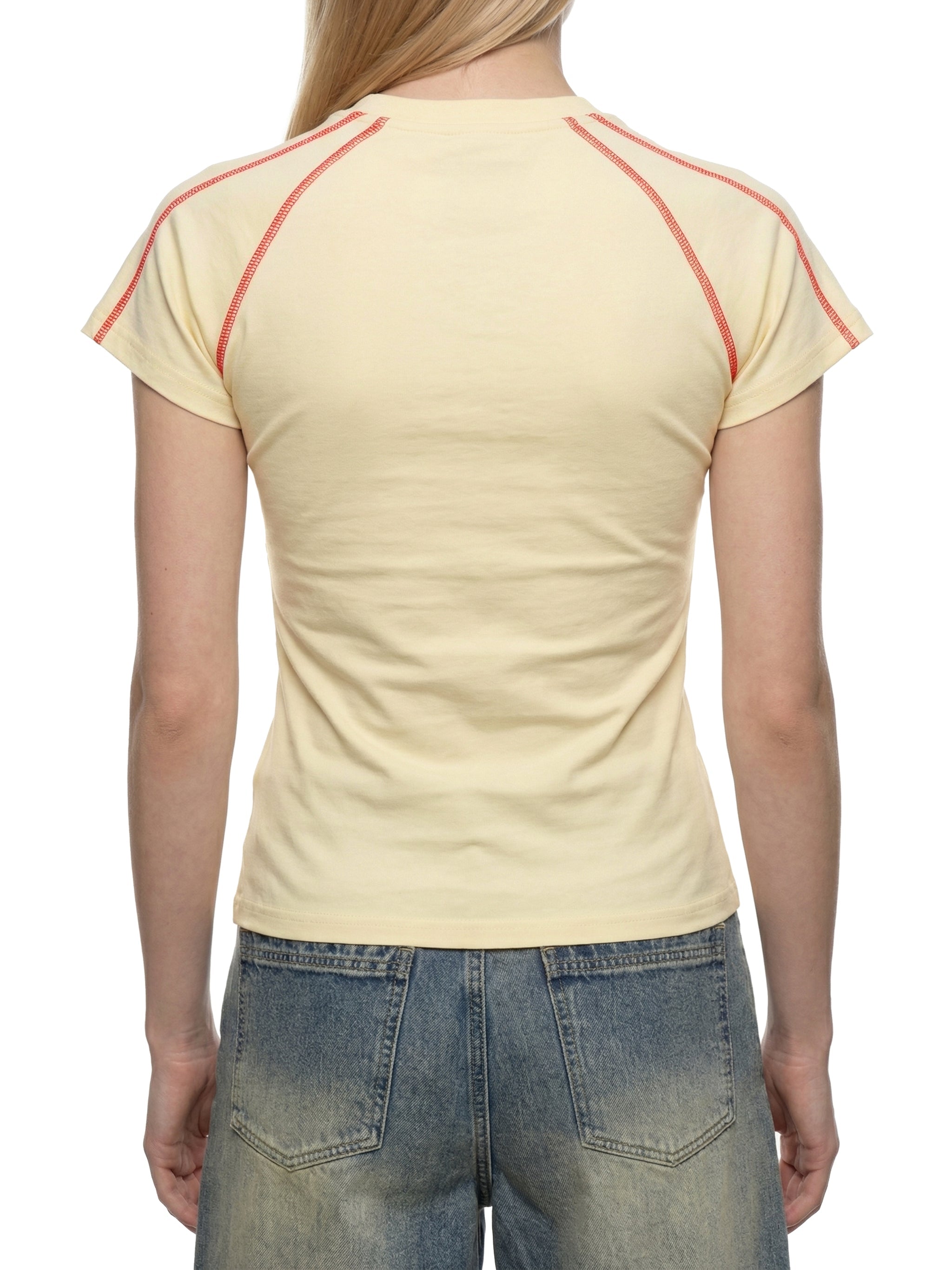 Back view of a woman wearing a cream raglan t-shirt with red contrast stitching and blue jeans